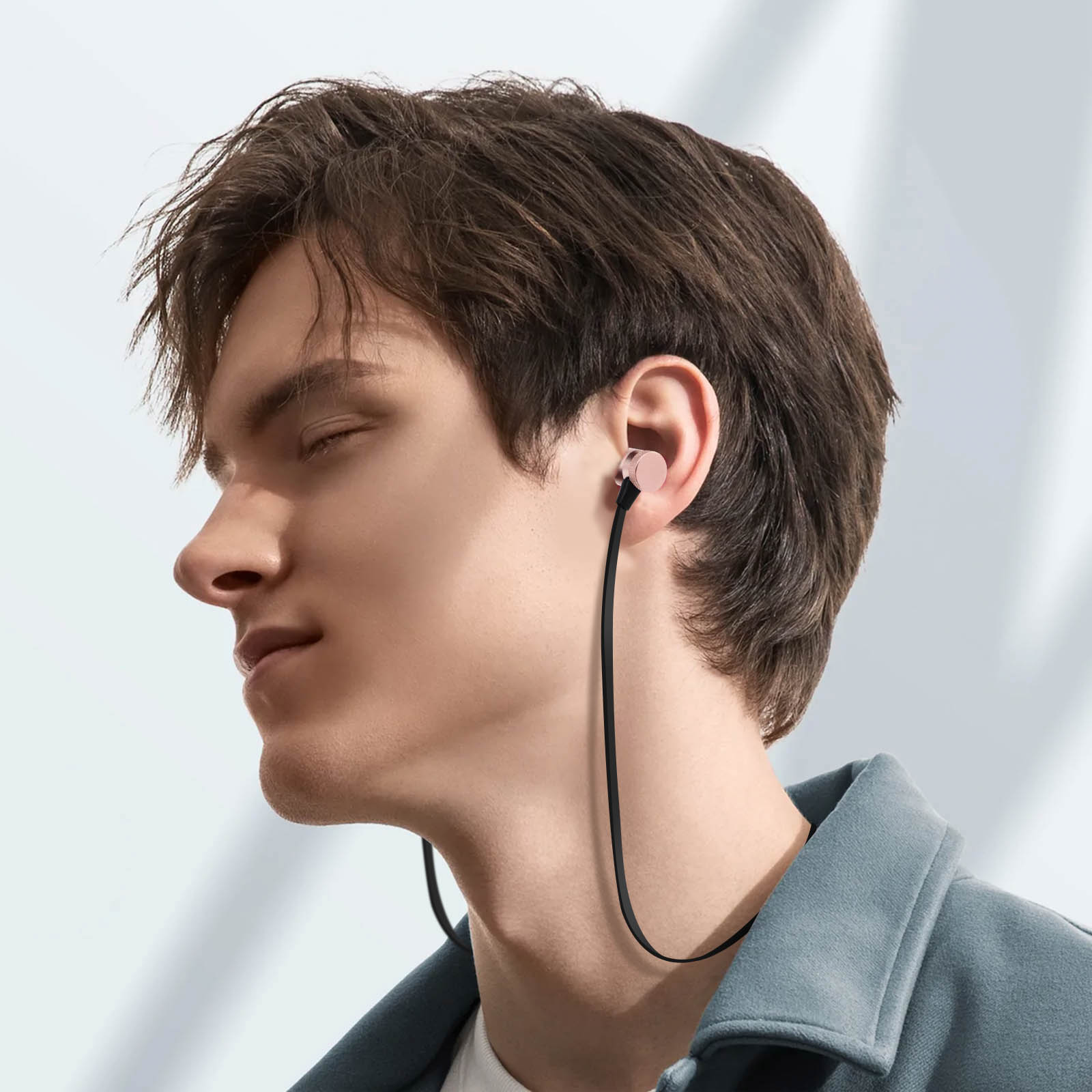Un uomo con auricolari. Indossa una giacca blu e gli auricolari e il cavo sono neri e rosa.