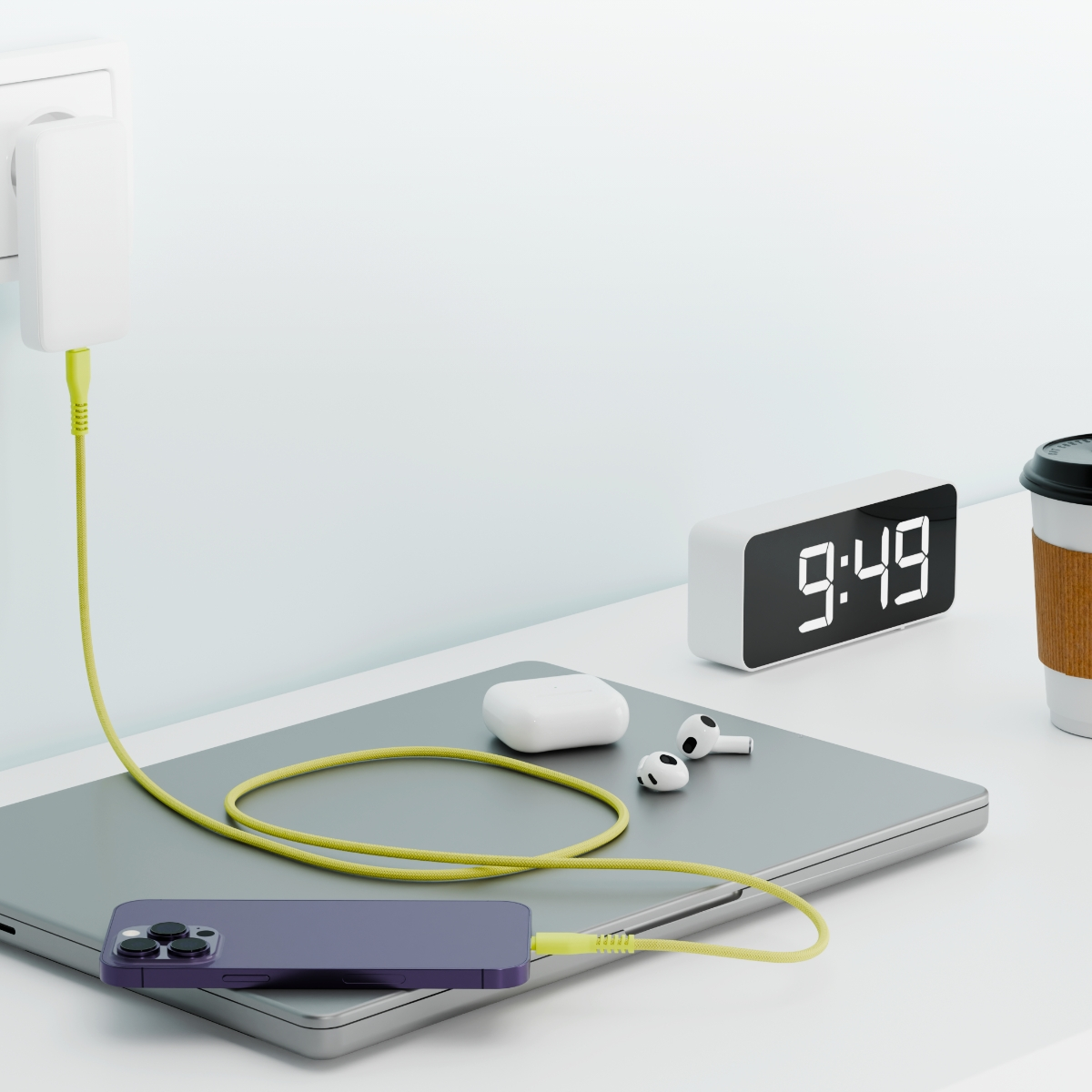 Laptop, telefon i kabel ładujący podłączone do gniazdka i zegara cyfrowego.