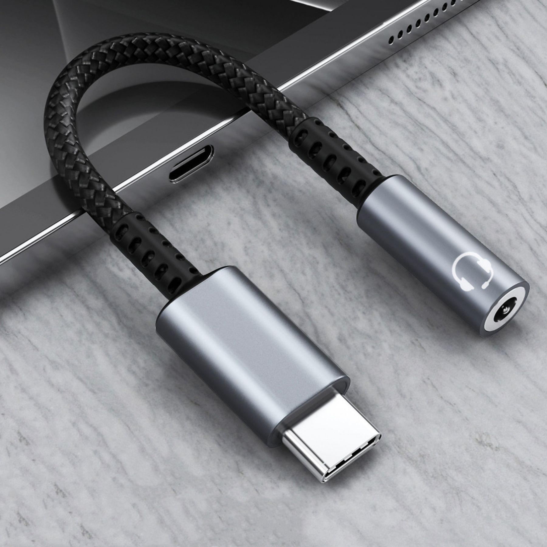 Silberner USB-C-auf-3,5-mm-Kopfhöreradapter. Schwarzes geflochtenes Kabel. An Tablet.