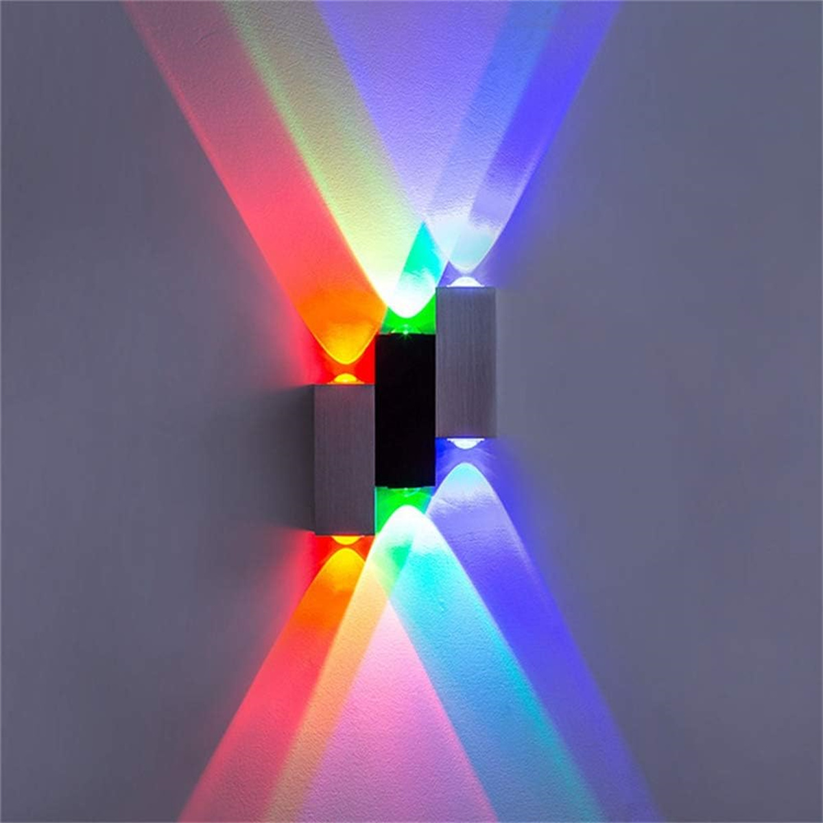 Eine Wand mit farbigen Lichtstrahlen, die von einer dekorativen Leuchte ausgehen. Die Lichter sind rot, grün und blau.