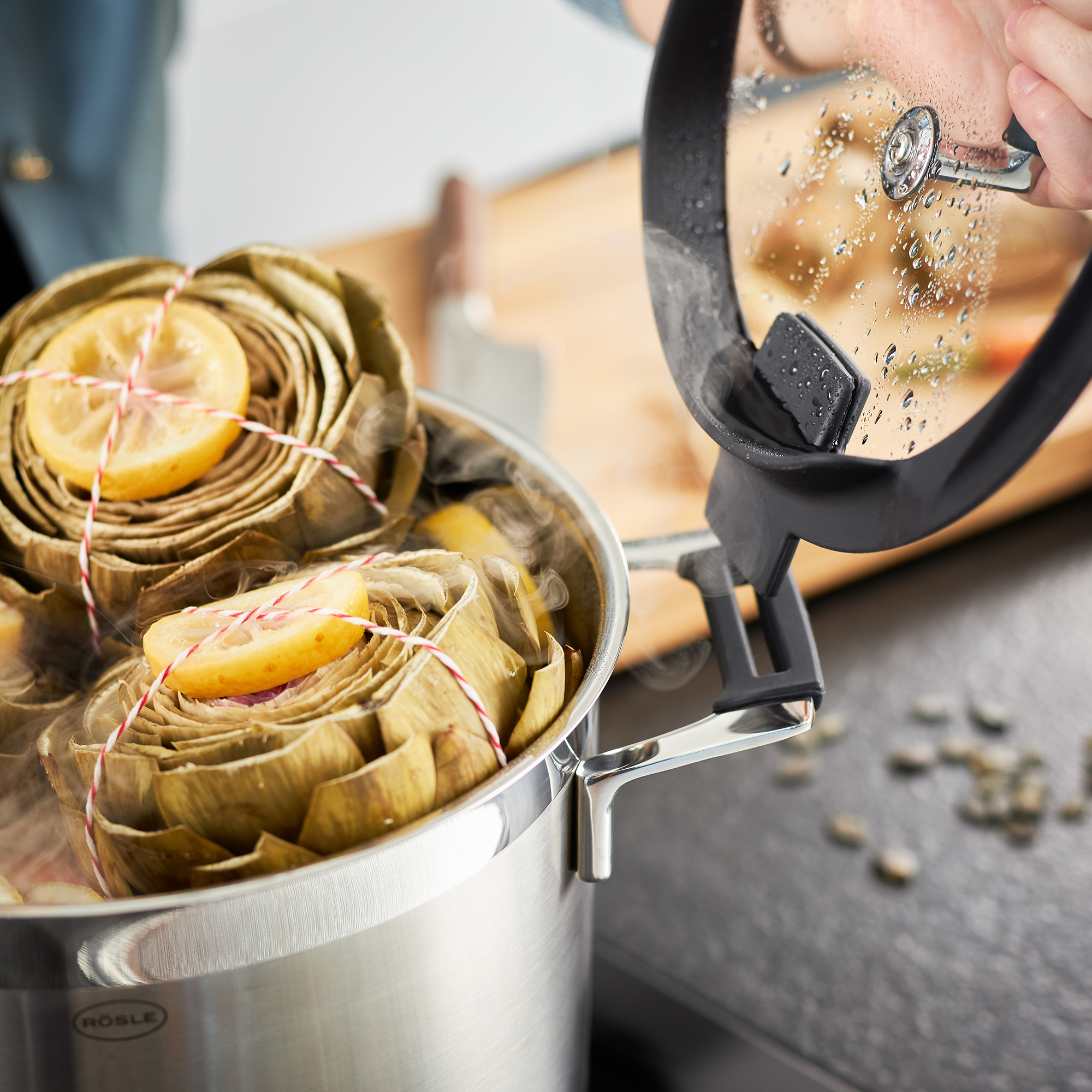 Une casserole en acier inoxydable avec des artichauts et des tranches de citron.
