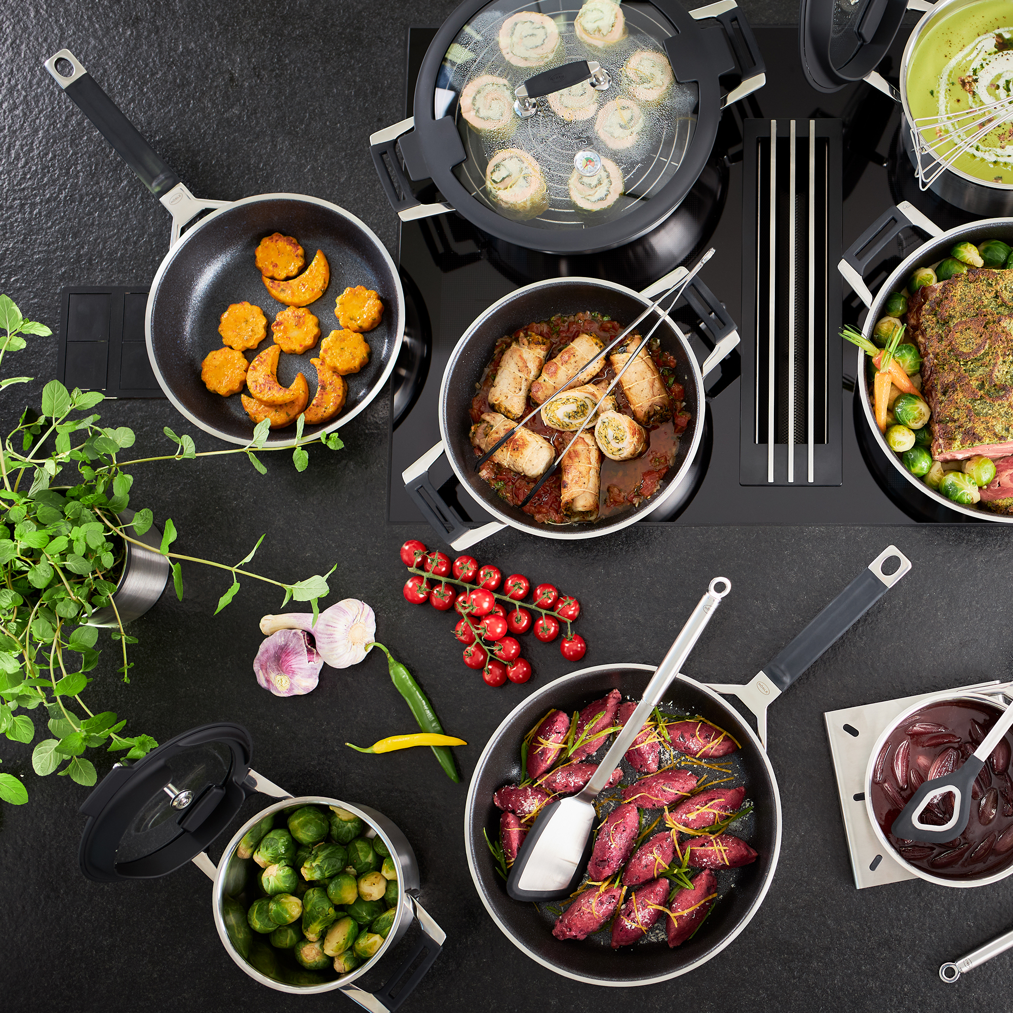 Scène de cuisine avec des poêles, de la nourriture et divers ustensiles de cuisine. Un comptoir noir.