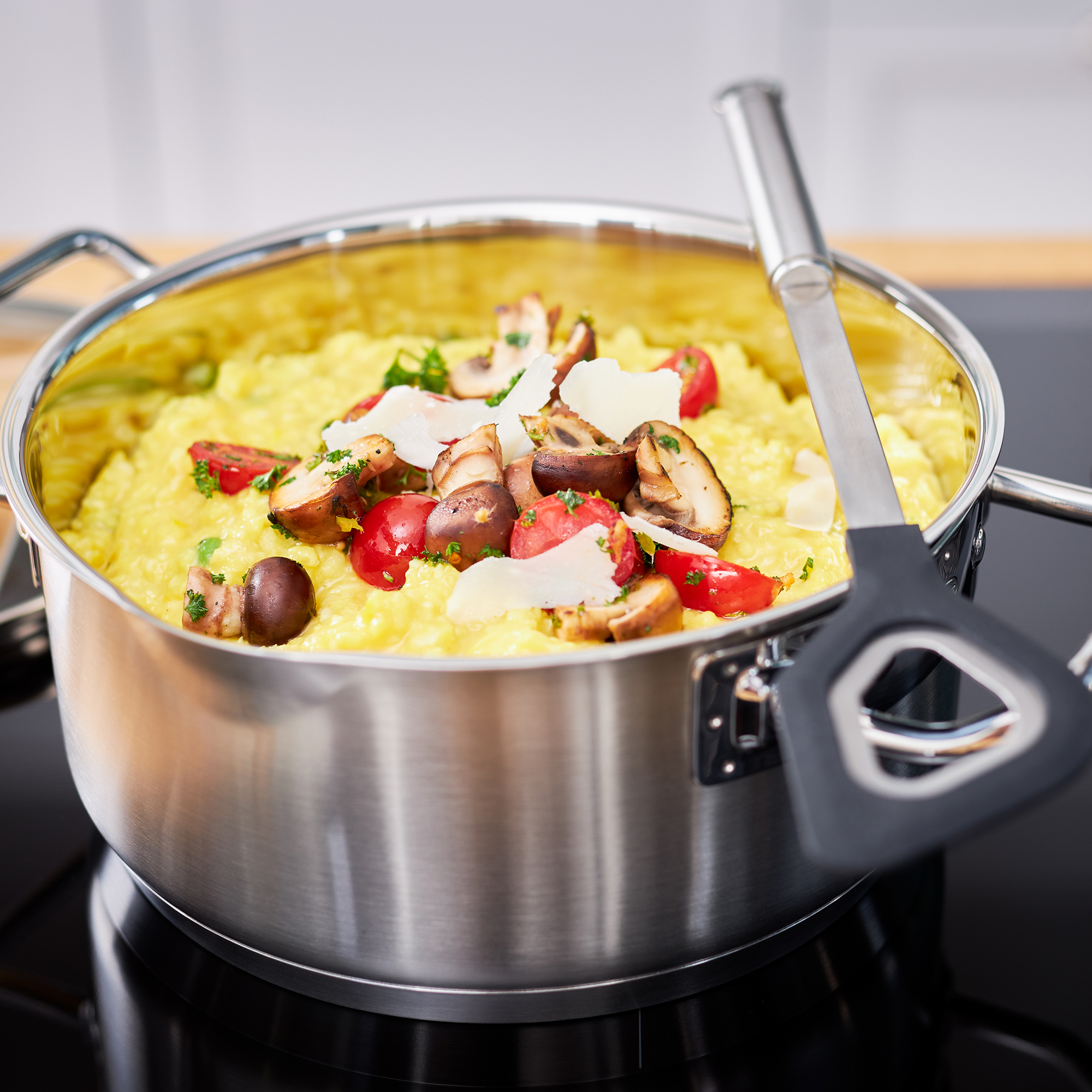 Pot avec de la nourriture cuite et une spatule. La nourriture est jaune avec des tomates et des champignons.