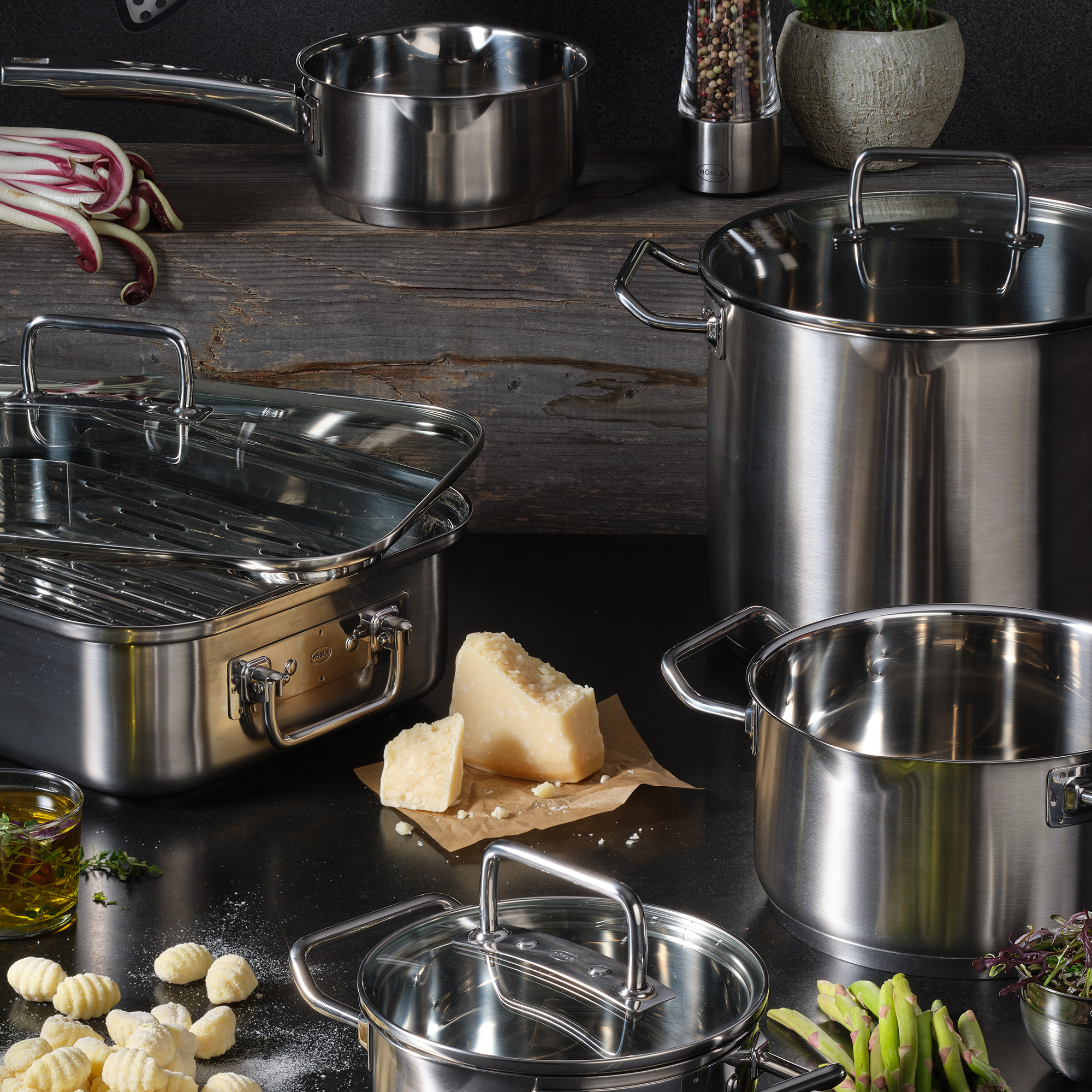 Scène de cuisine avec divers casseroles et poêles en acier inoxydable. Parmesan, gnocchis et ingrédients.