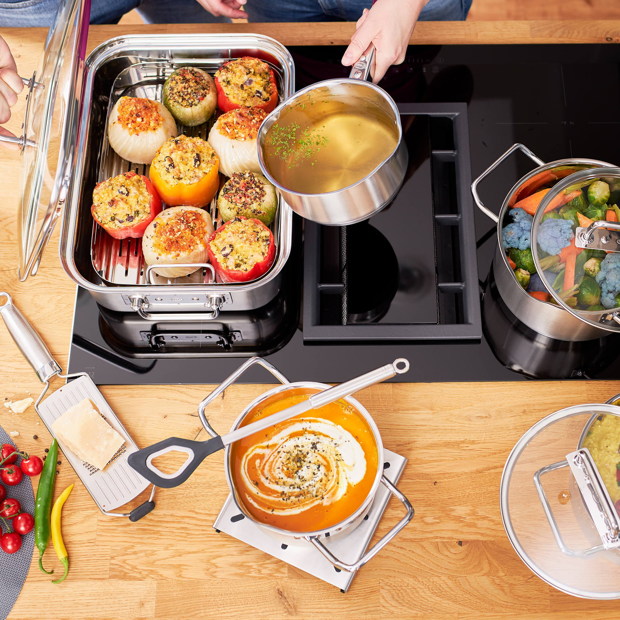Scène de cuisine : Tomates farcies, soupe, légumes et une personne versant du liquide d'une casserole.