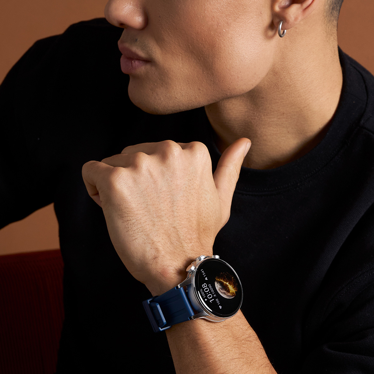Homme portant une smartwatch au poignet, bracelet bleu, sur fond marron.