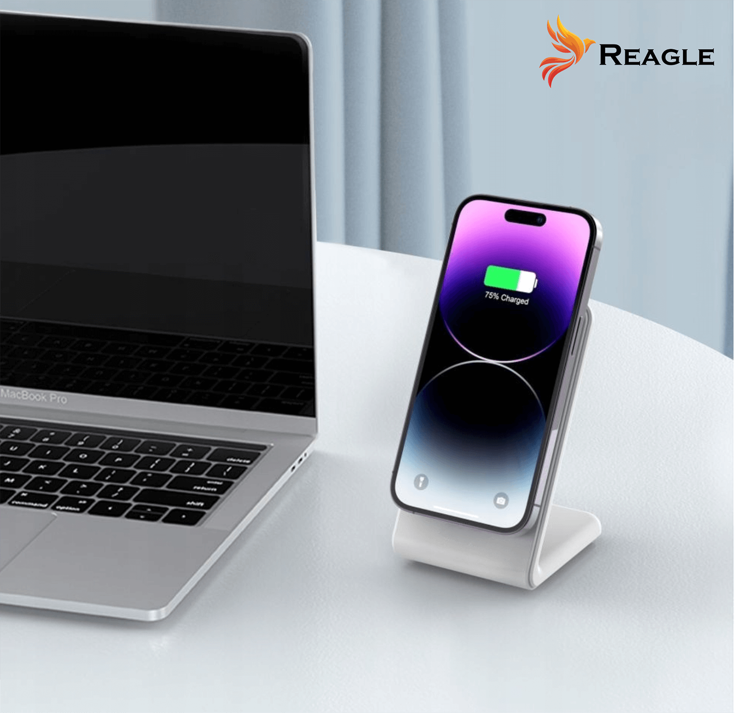 Laptop i telefon ładujący się na białym stojaku. Telefon pokazuje 75% naładowania. Logo to REAGLE.