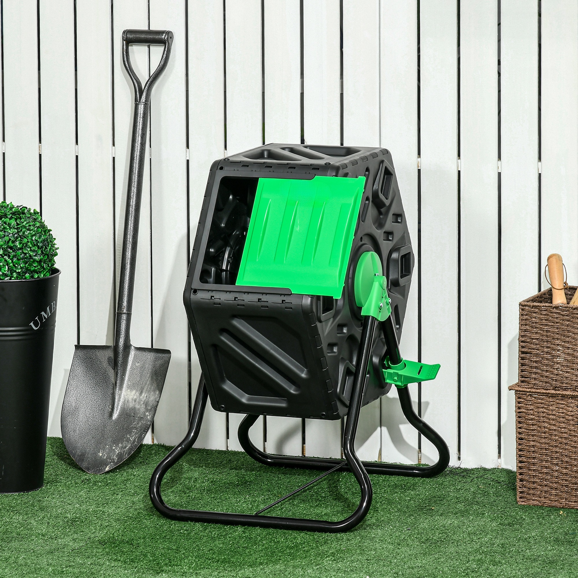 Komposttrommler in einem Garten. Eine Schaufel und eine kleine Pflanze sind im Bild.