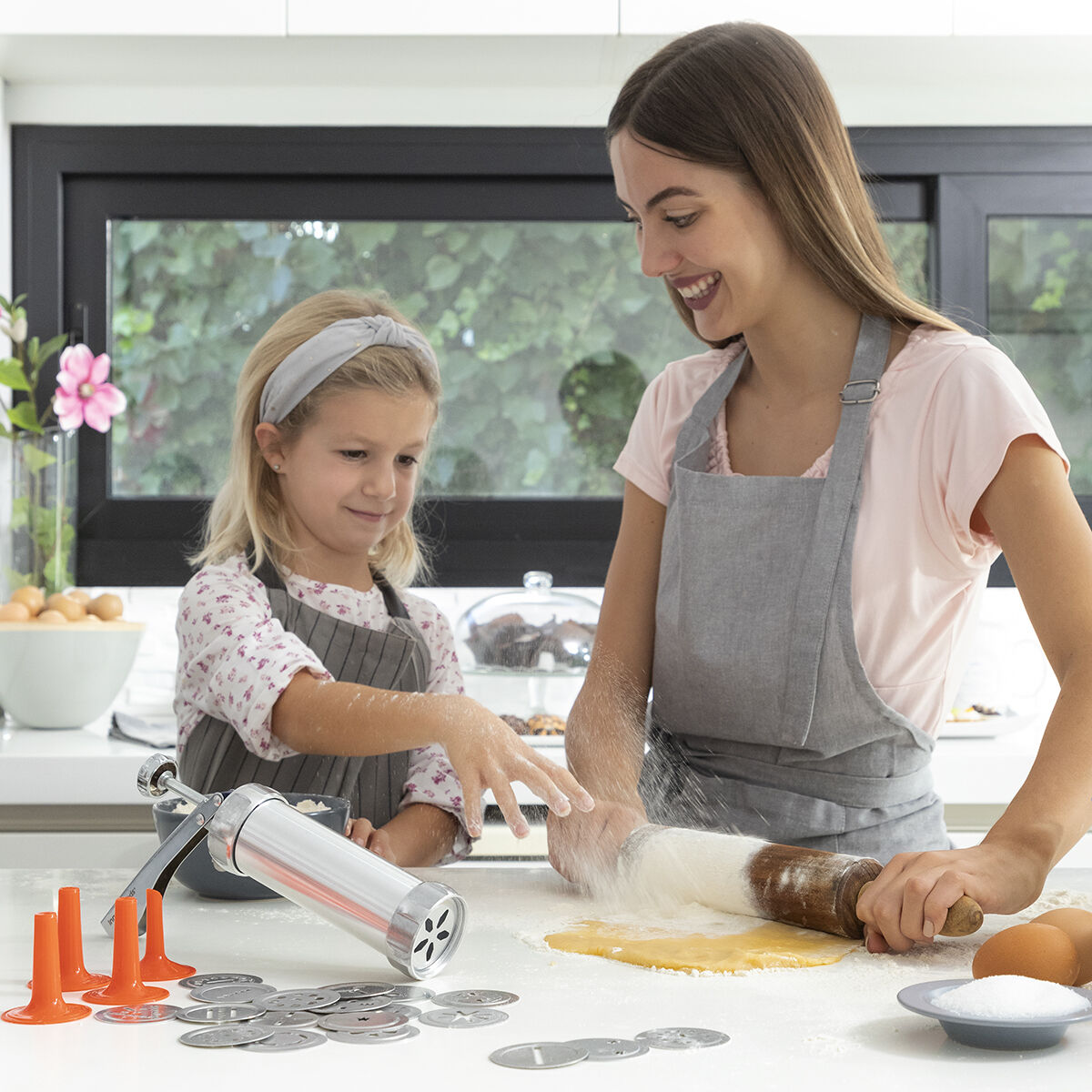 Donna e bambino che cuociono biscotti. Spolverare la farina. Scena di cucina.