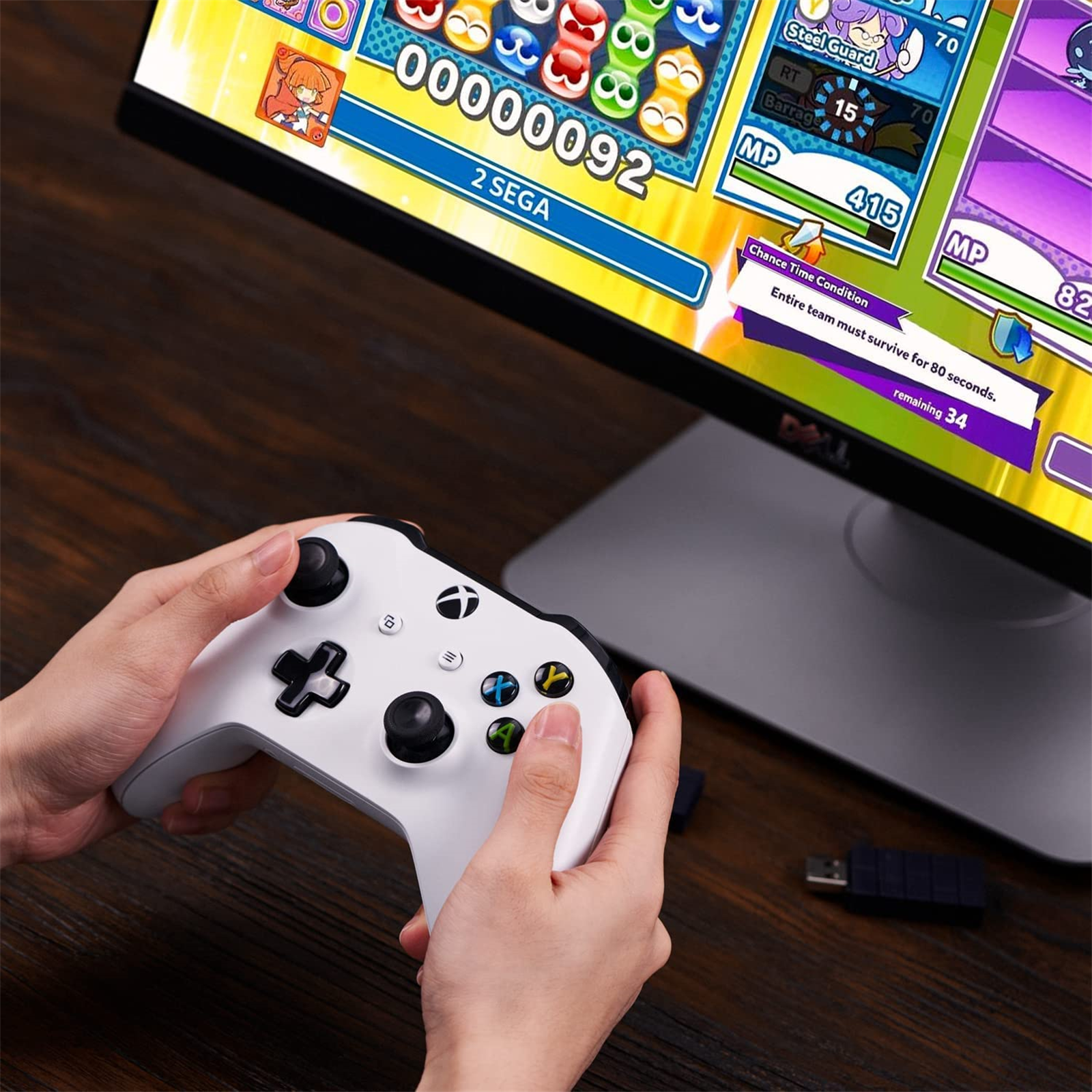 Hände halten einen weißen Xbox-Controller und spielen ein Spiel auf einem Monitor. Das Spiel wird angezeigt.