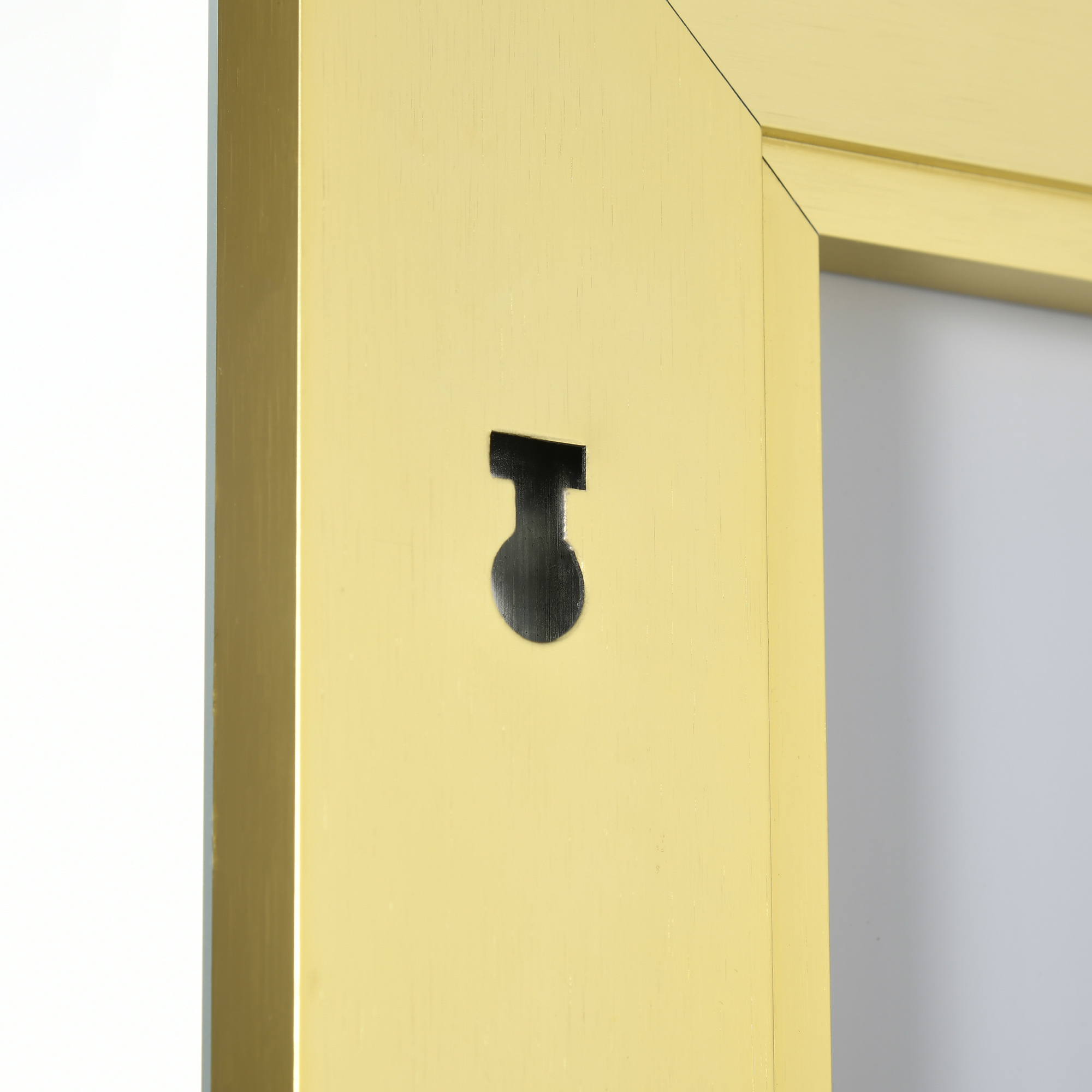 Nahaufnahme einer Wand mit einem schwarzen Metallhaken, der an einem goldenen Rahmen befestigt ist. Der Hintergrund ist weiß.