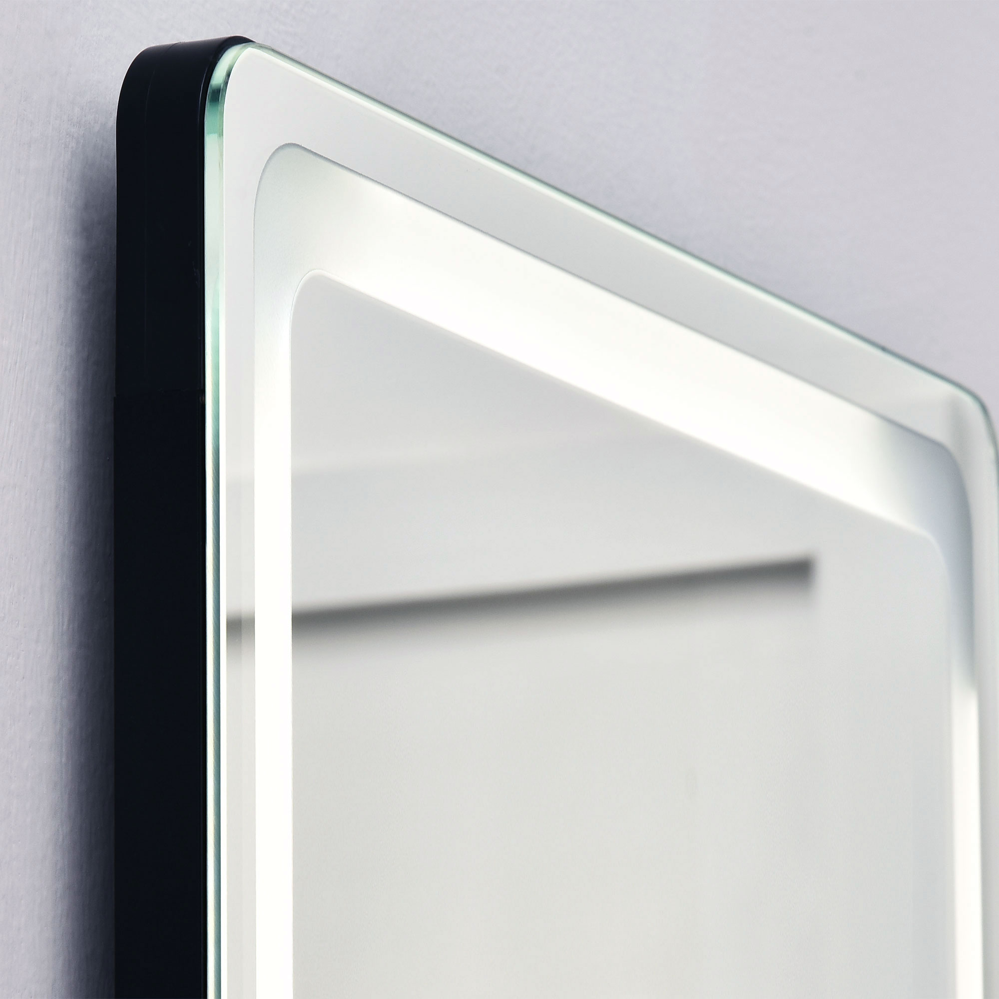 Nahaufnahme eines schwarz gerahmten Spiegels mit weißem LED-Rand, der einen weißen Hintergrund reflektiert.