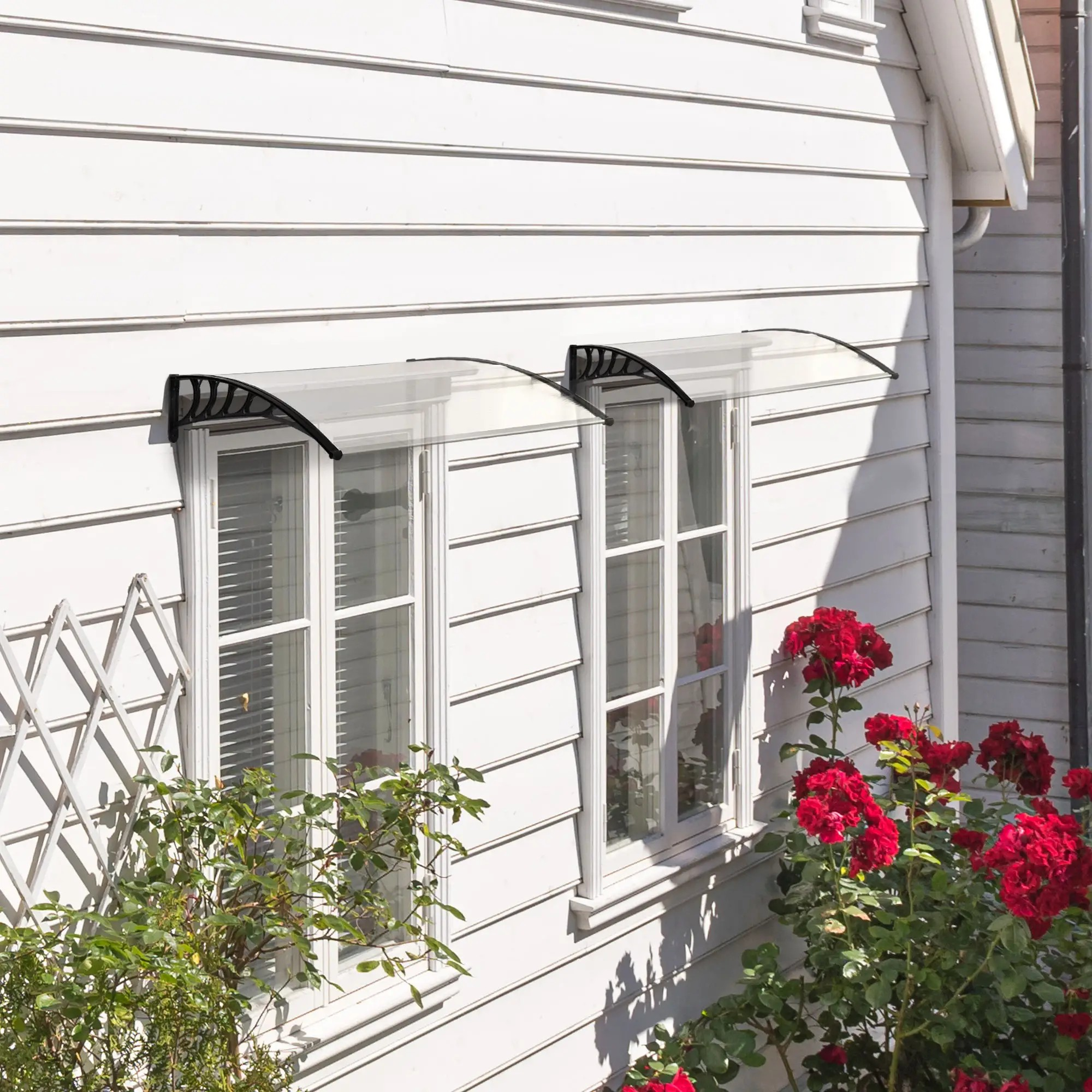 Zwei Fenster mit transparenten Markisen, roten Rosen und weißer Verkleidung.