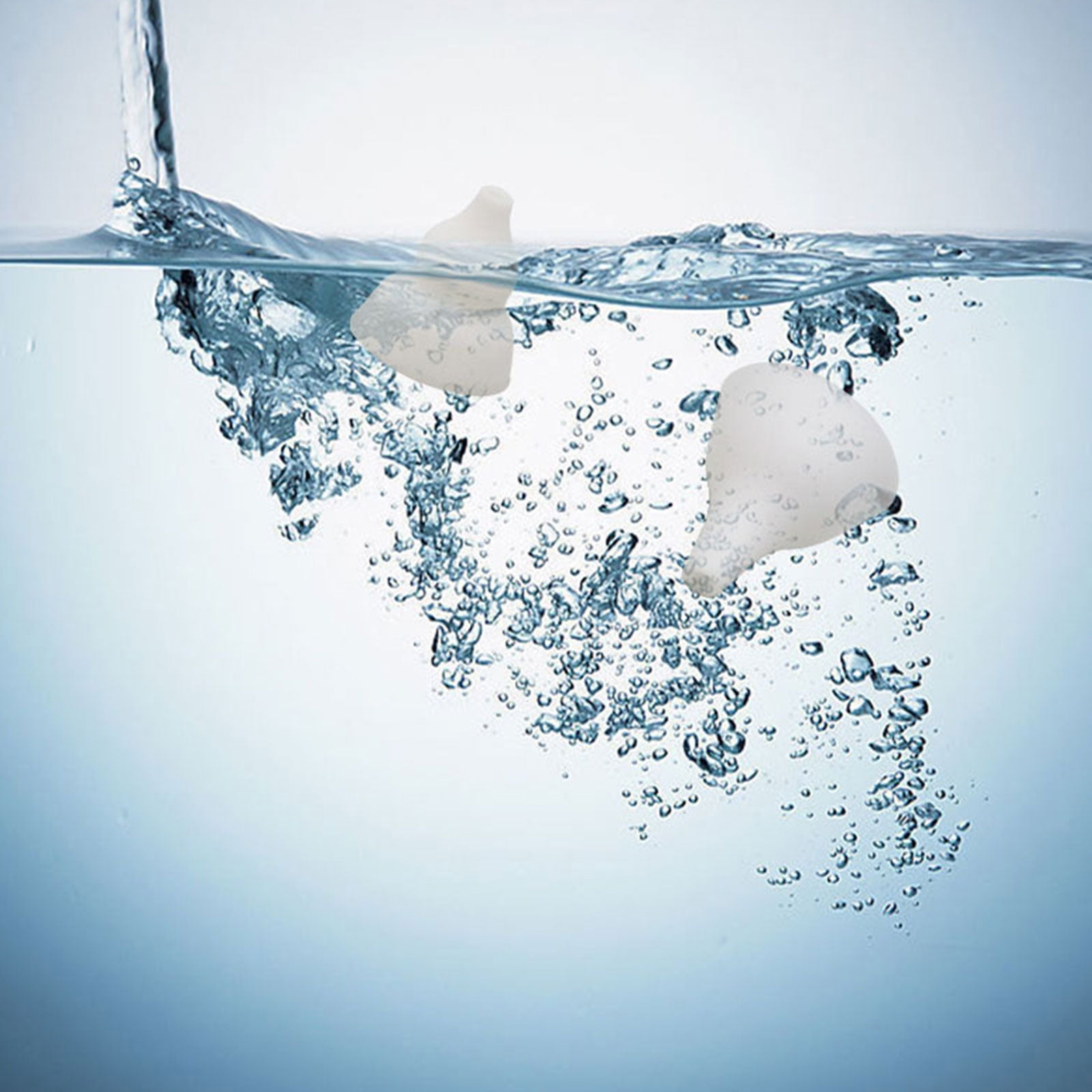 Zwei weiße Silikonnippel im Wasser. Blasen umgeben die Nippel.
