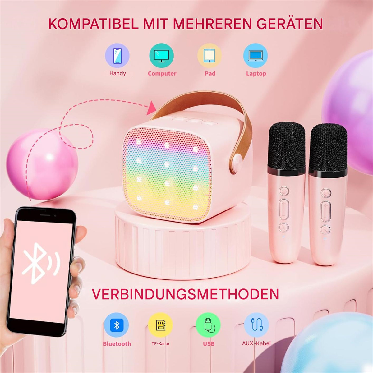 Ein rosa Lautsprecher mit Regenbogen-Lichtanzeige, ein Telefon und zwei Mikrofone. Der Lautsprecher steht auf einem Ständer.