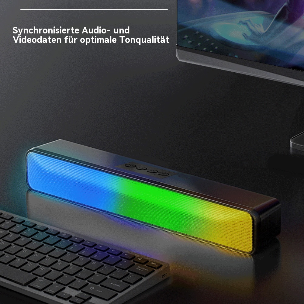 Schwarze Soundbar mit blauen, grünen und gelben Lichtern. Eine Tastatur liegt davor auf dem Schreibtisch.