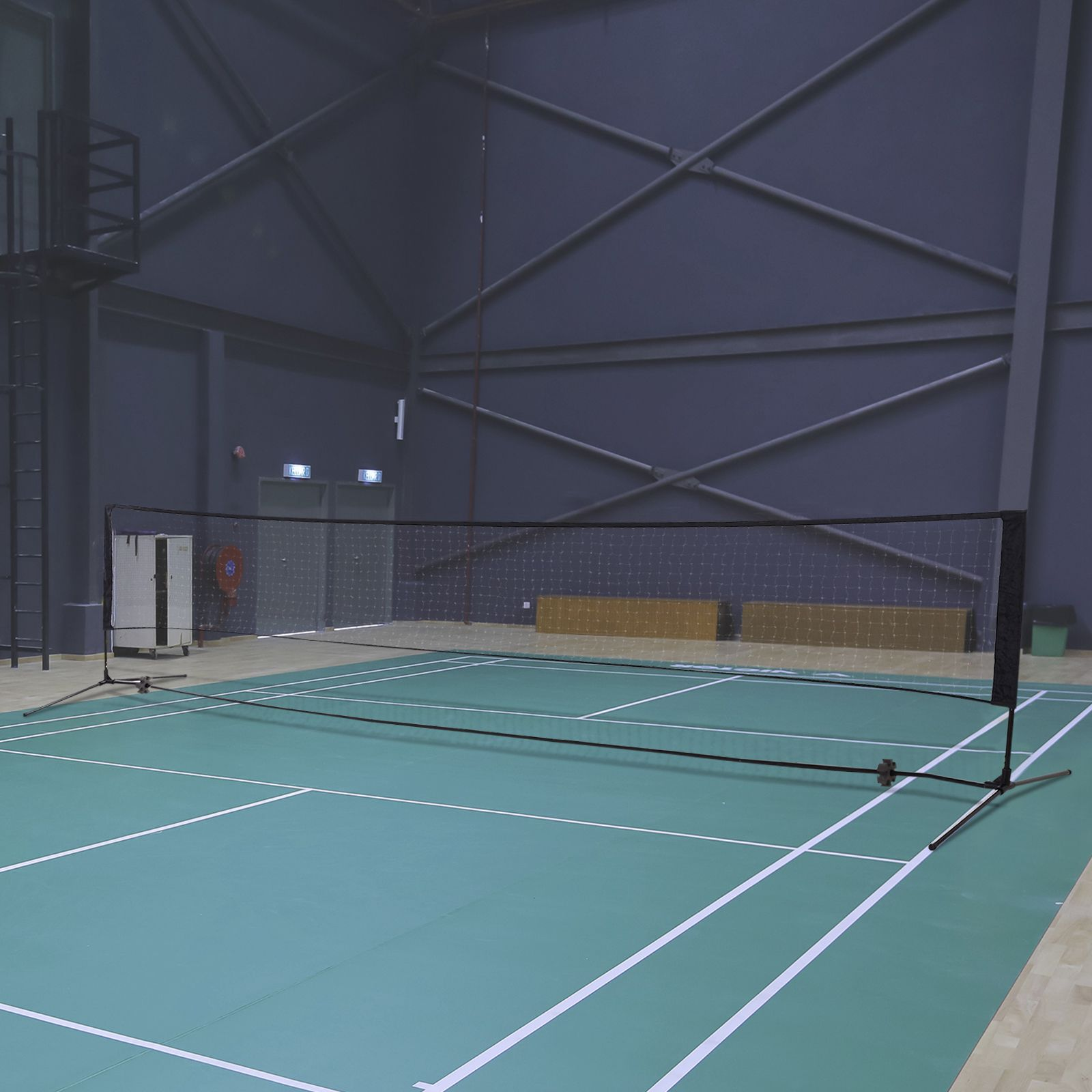 Badmintonnetz in einer großen Sporthalle. Grüner Boden, weiße Linien, dunkle Wände.