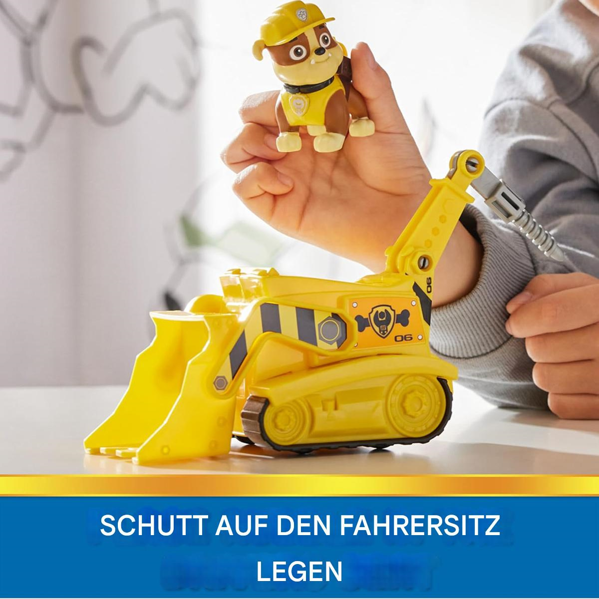 Kinderhand legt einen Spielzeughund in einen gelben Bau-Bagger.