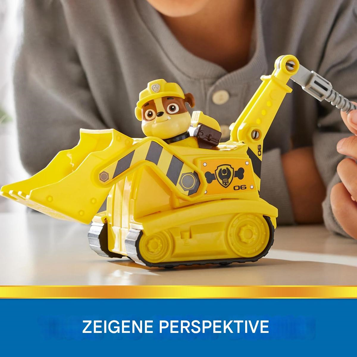 Ein Kind spielt mit einem gelben Paw Patrol-Konstruktionsspielzeug. Text: Zeigt Perspektive.