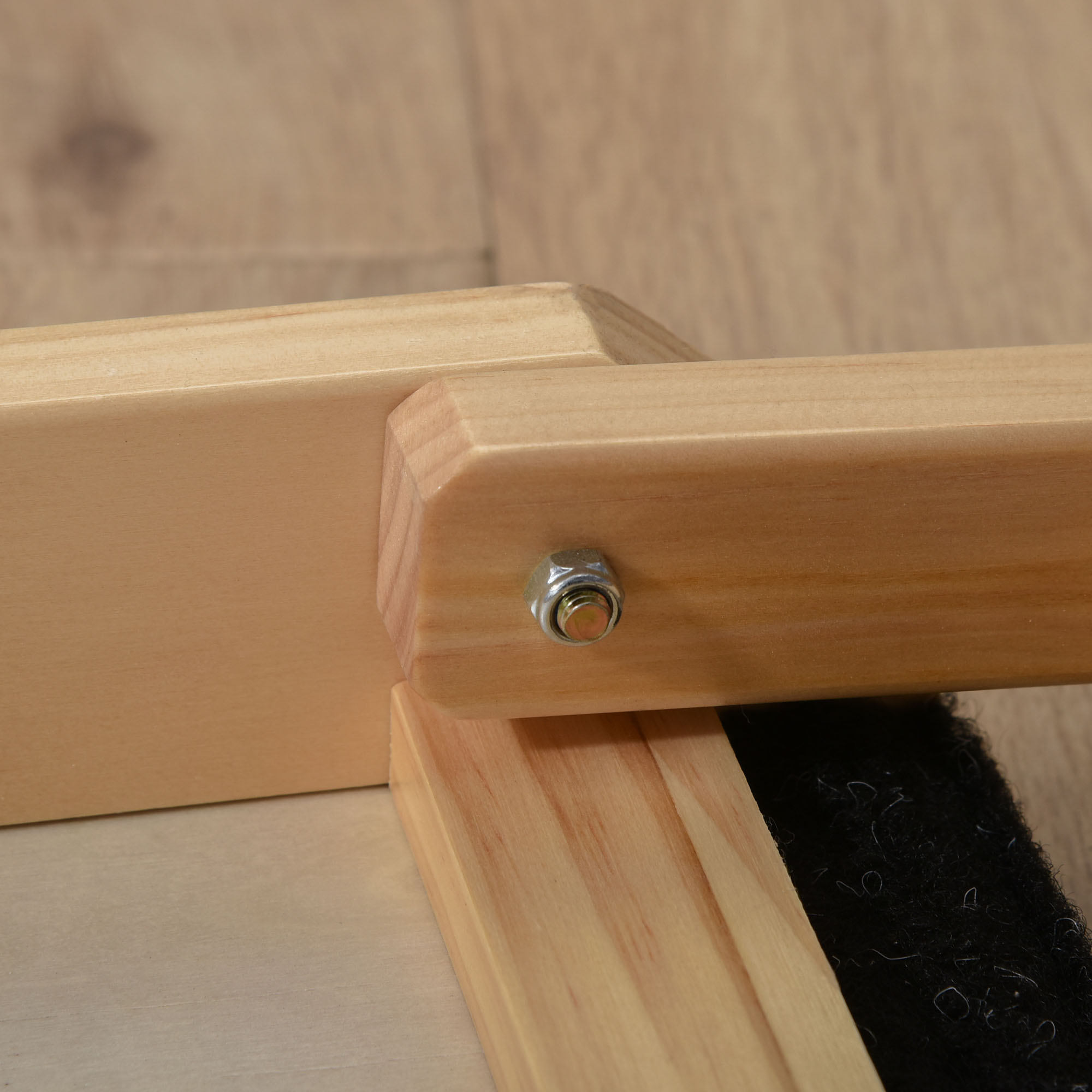 Nahaufnahme einer Hunde-Rampenverbindung mit Schraube, Holz und schwarzer Oberfläche.