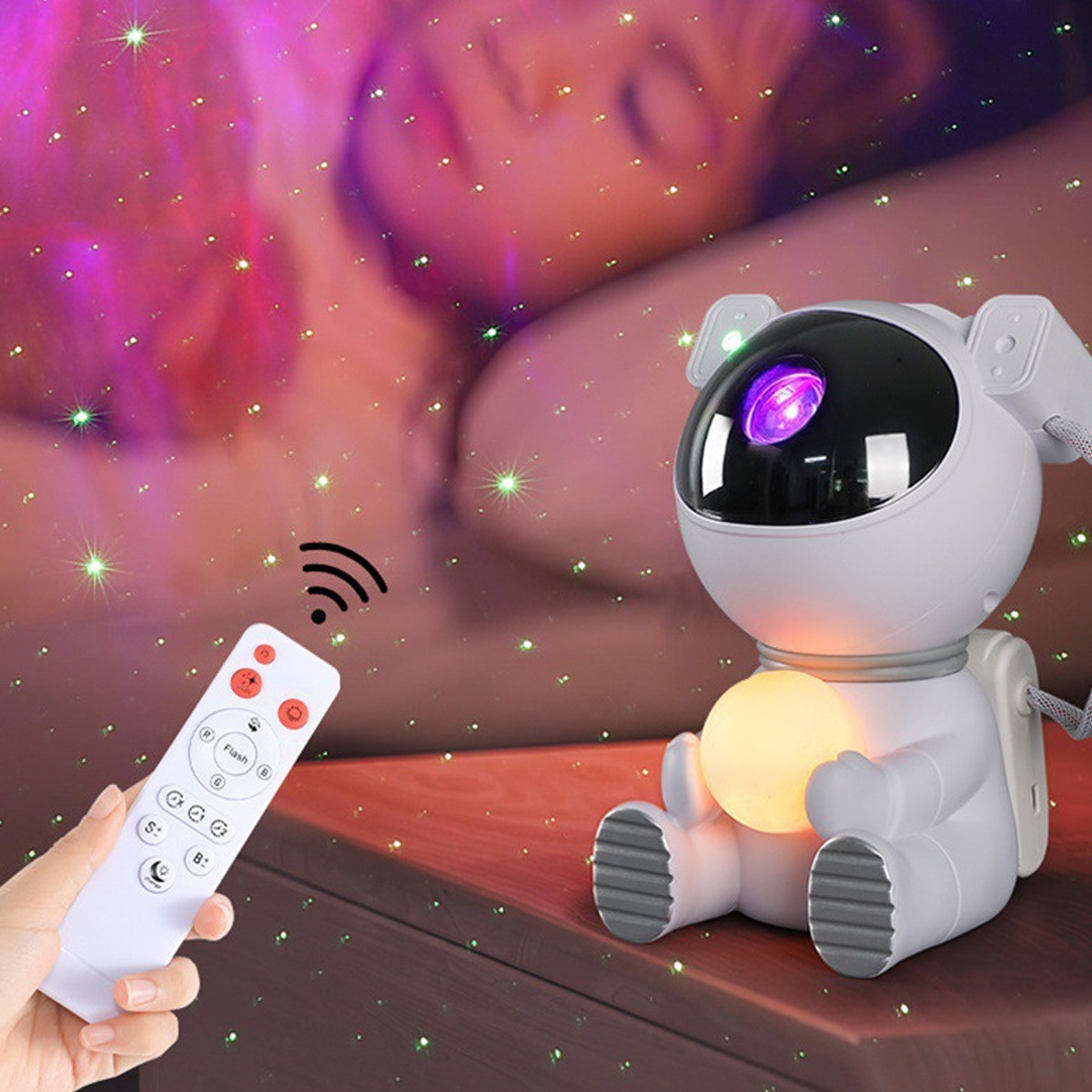 Astronauten-Projektorlampe mit Fernbedienung. Eine Hand hält die Fernbedienung, im Hintergrund Sterne.