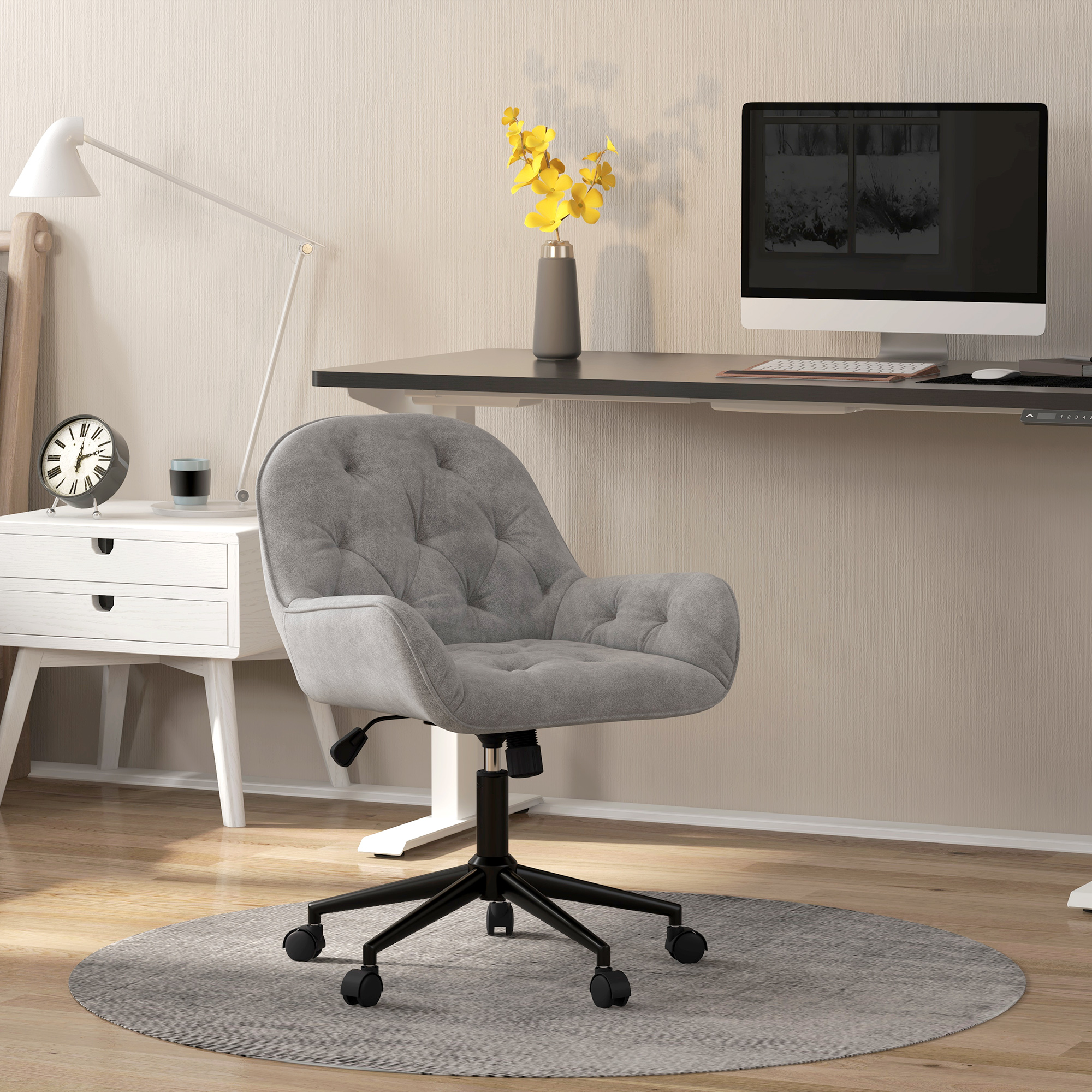 Ein grauer, getufteter Bürostuhl steht vor einem Schreibtisch mit Monitor und Lampe in einem Homeoffice.