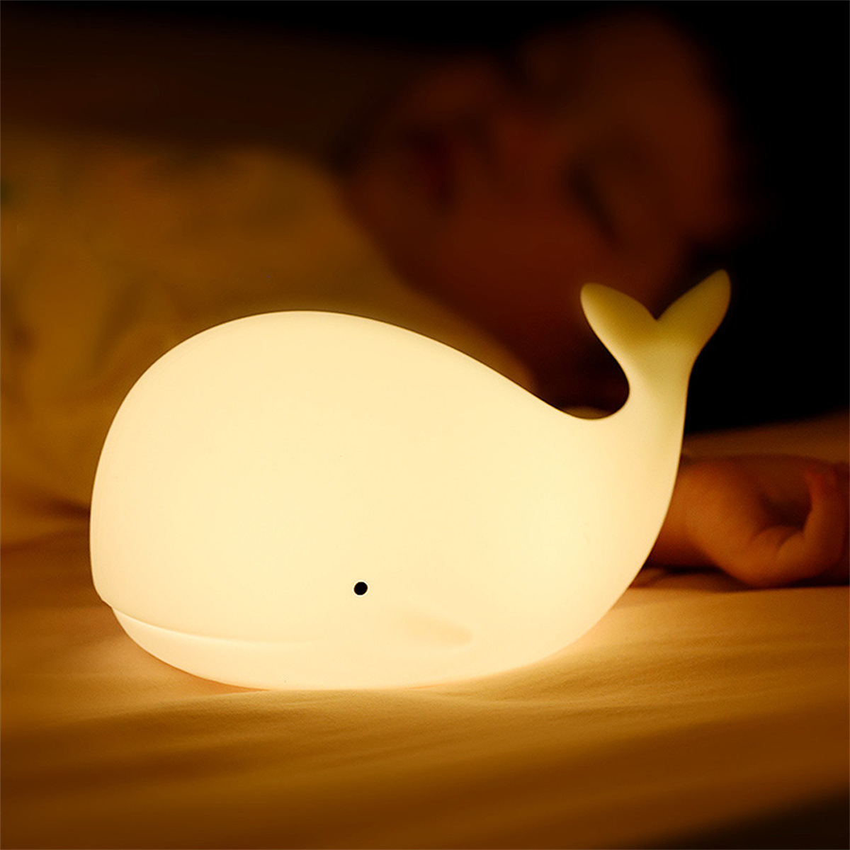Weißes walförmiges Leuchten auf einem Bett. Eine Person ist im Hintergrund. Gedämpfte Beleuchtung.
