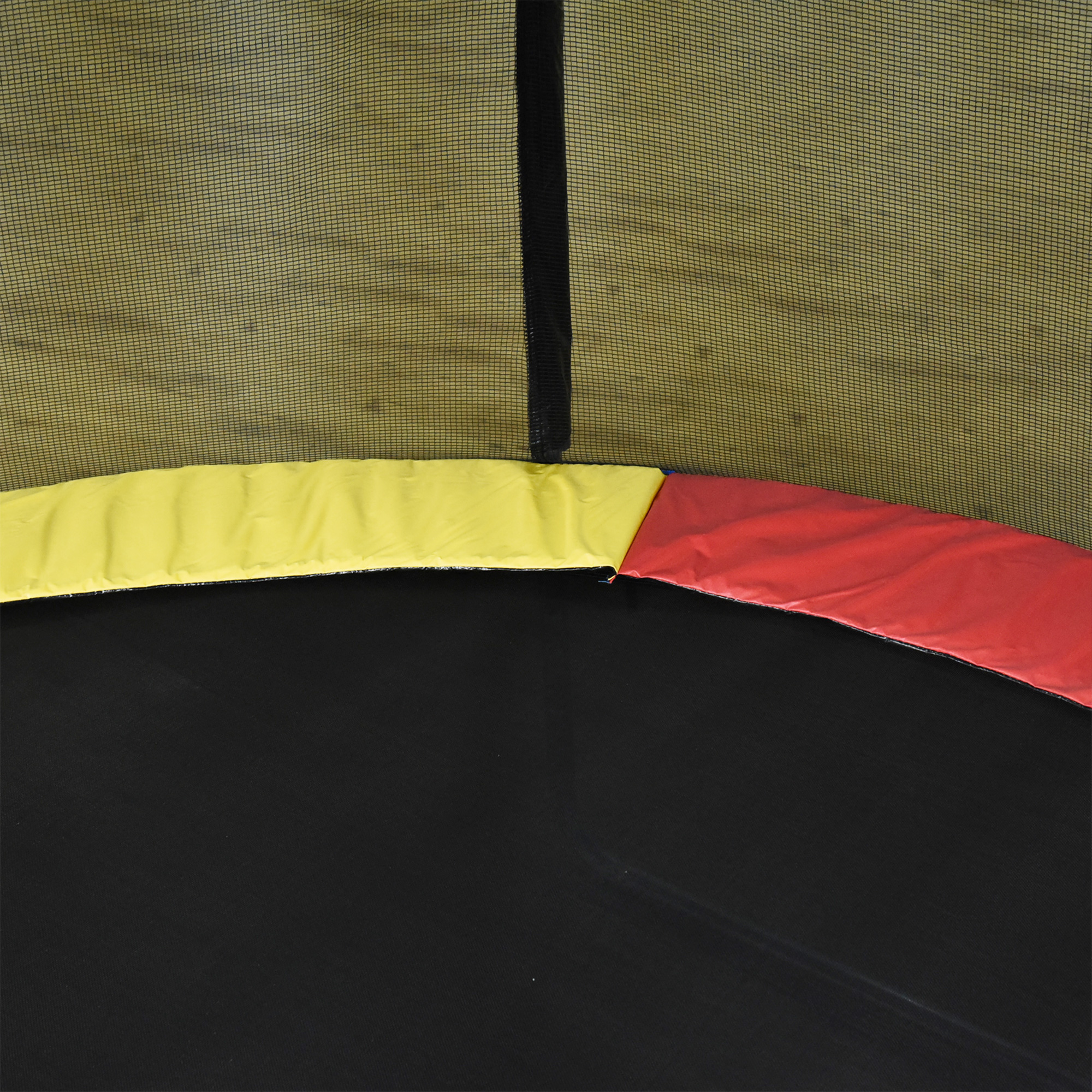 Teil eines Trampolins mit gelben, roten und schwarzen Abschnitten. Netz im Hintergrund.