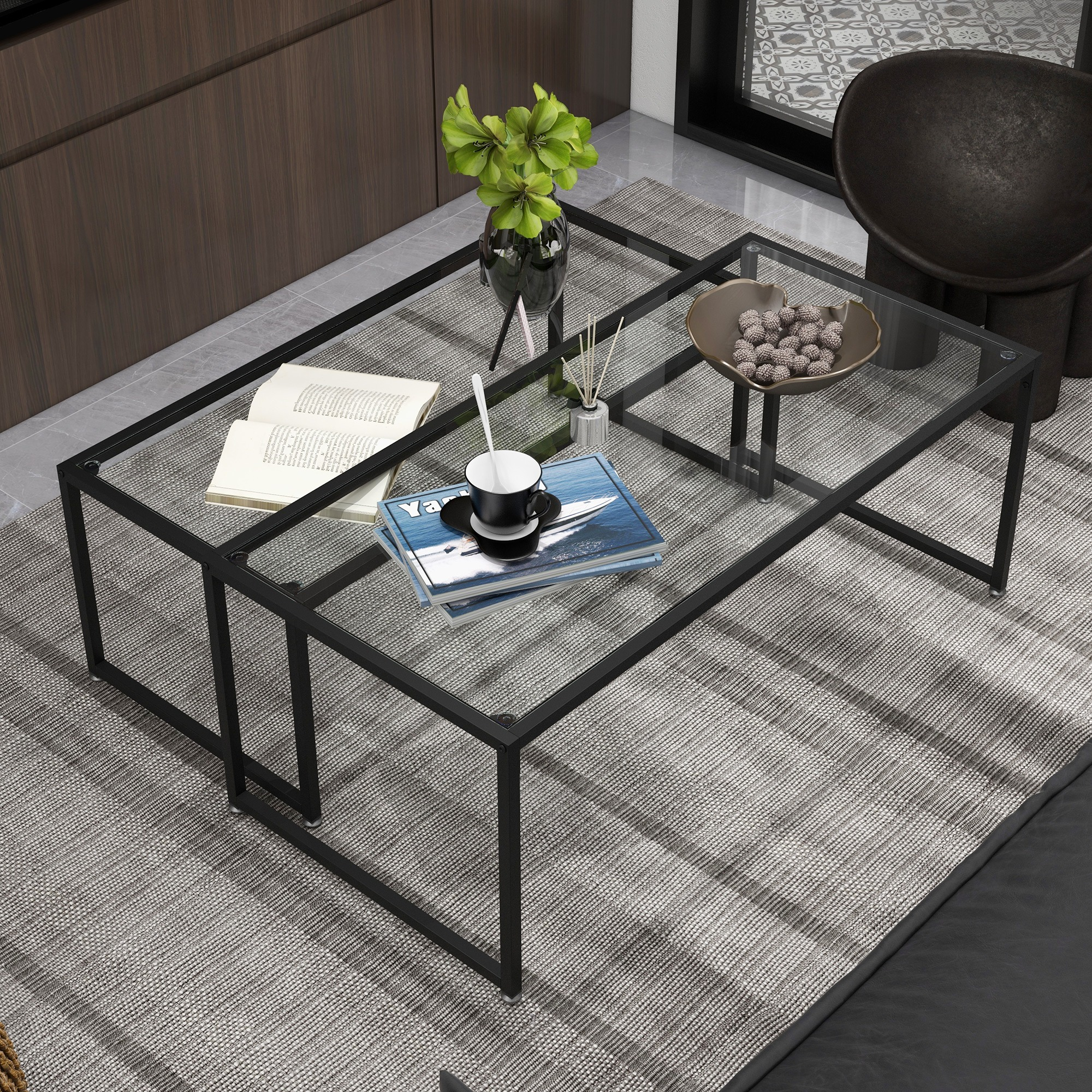 Zwei Tische mit Glasplatten und schwarzen Metallrahmen, mit Büchern, Vase und Deko.
