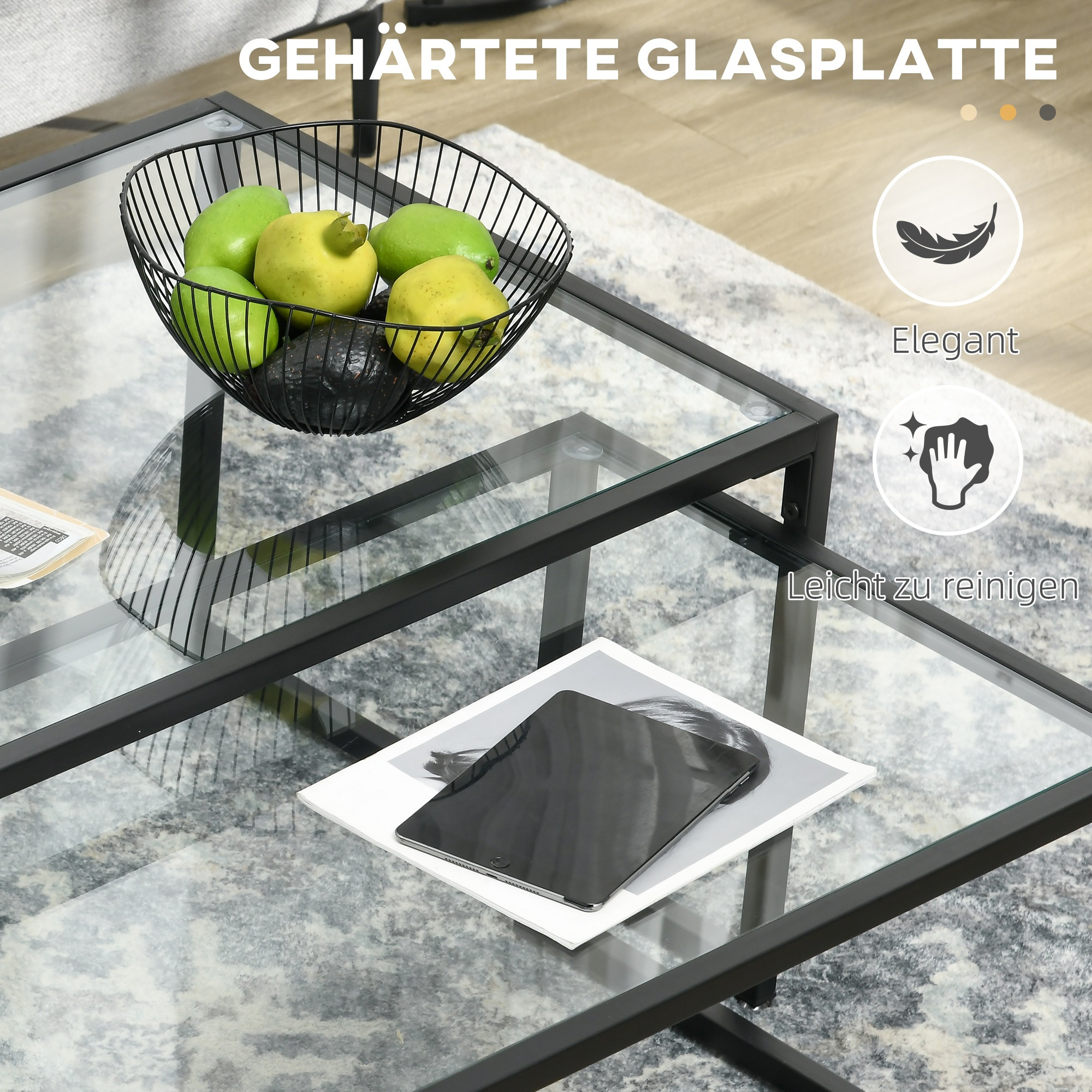 Ein Glastisch mit schwarzem Metallrahmen. Auf dem Tisch befinden sich eine Schüssel mit Obst und ein Tablet.