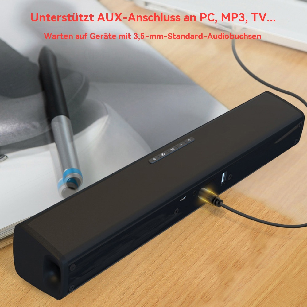 Eine schwarze Soundbar mit einem Kabel, das angeschlossen ist. Auf dem Holztisch liegen ein Stift und ein Laptop.