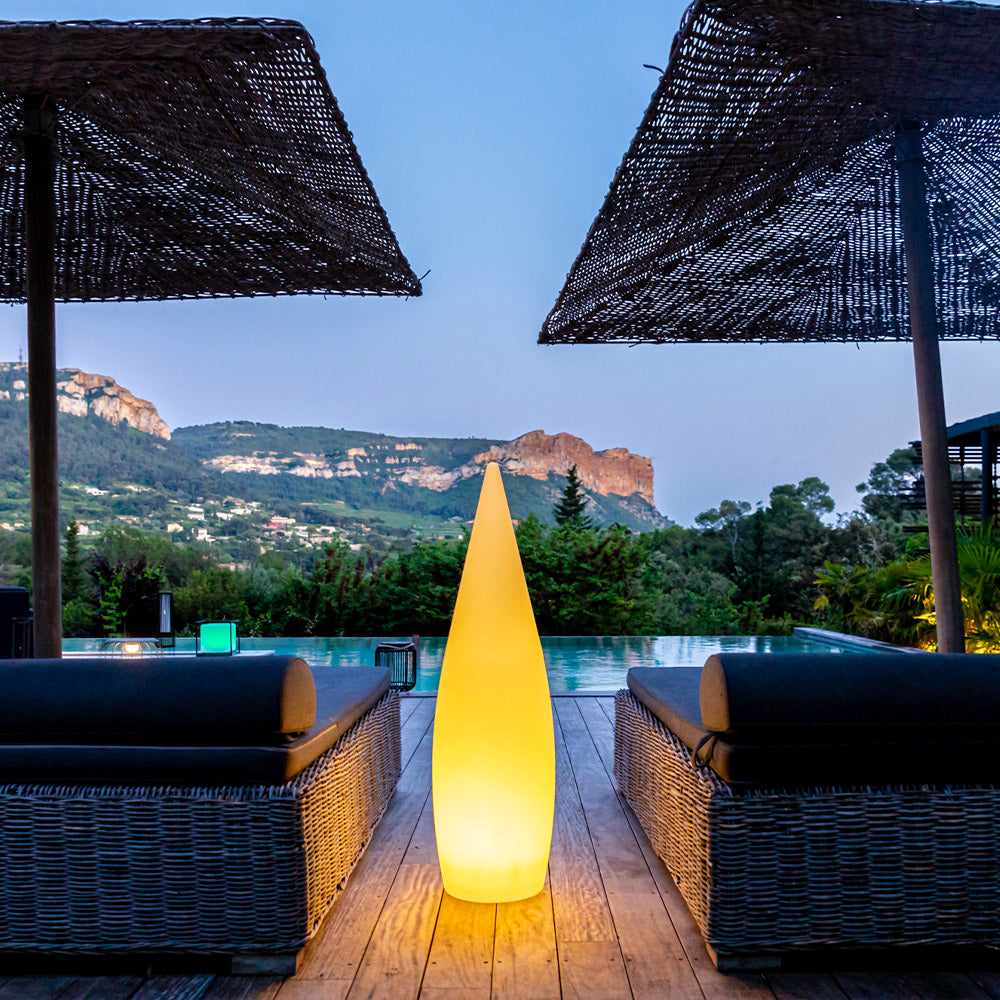 Eine leuchtende, gelbe Leuchte in einem Poolbereich mit Bergen im Hintergrund.