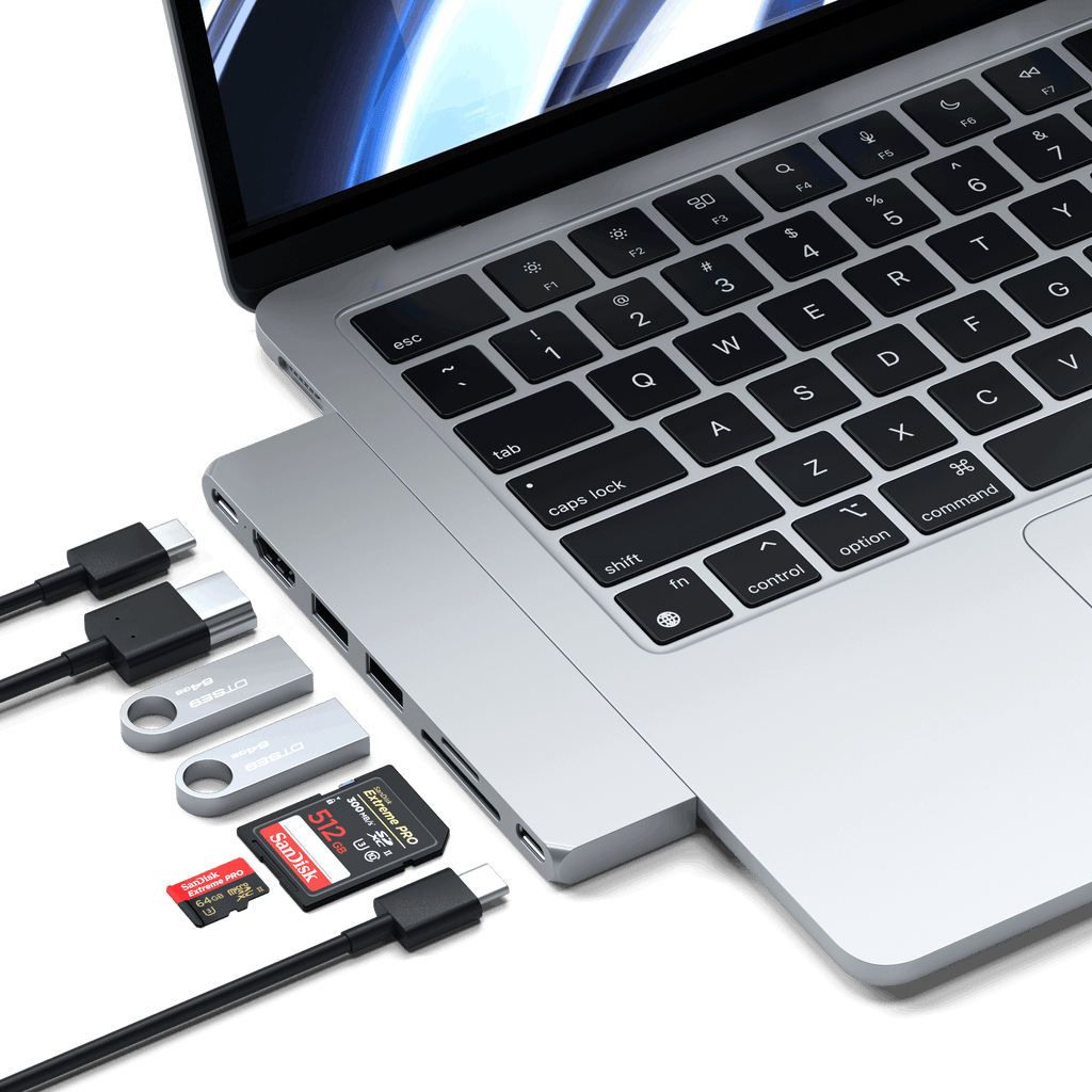 Portátil con puertos USB-C, conectado a varias unidades USB y tarjetas SD, todo sobre fondo blanco.