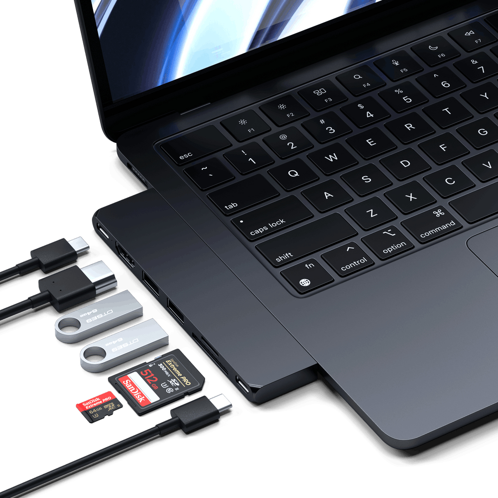 Portátil con puertos USB-C, conectado a varias unidades USB y tarjetas SD, todo sobre fondo oscuro.