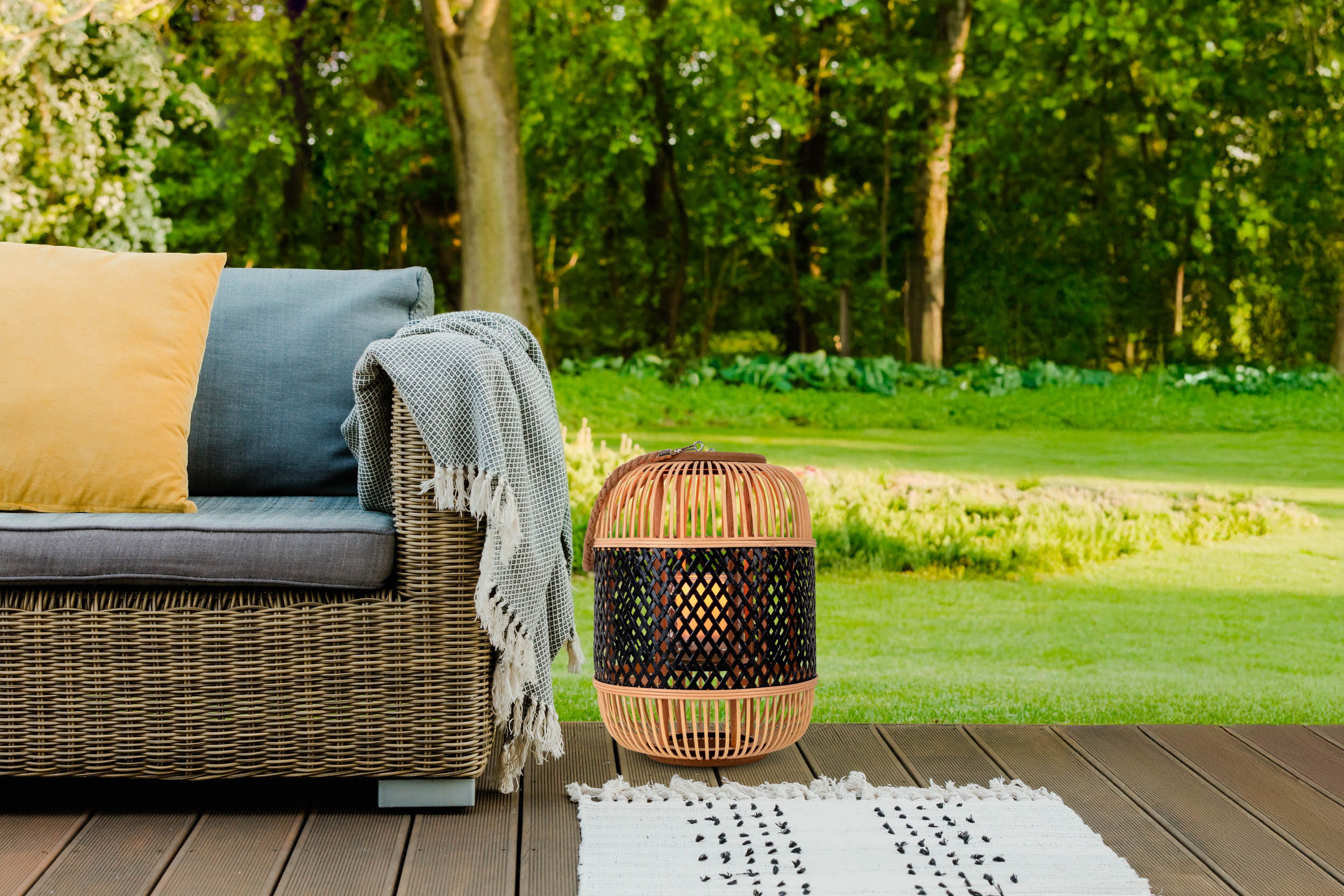 Eine Bambuslaterne auf Deck, mit Sofa und Teppich, grüner Rasen.