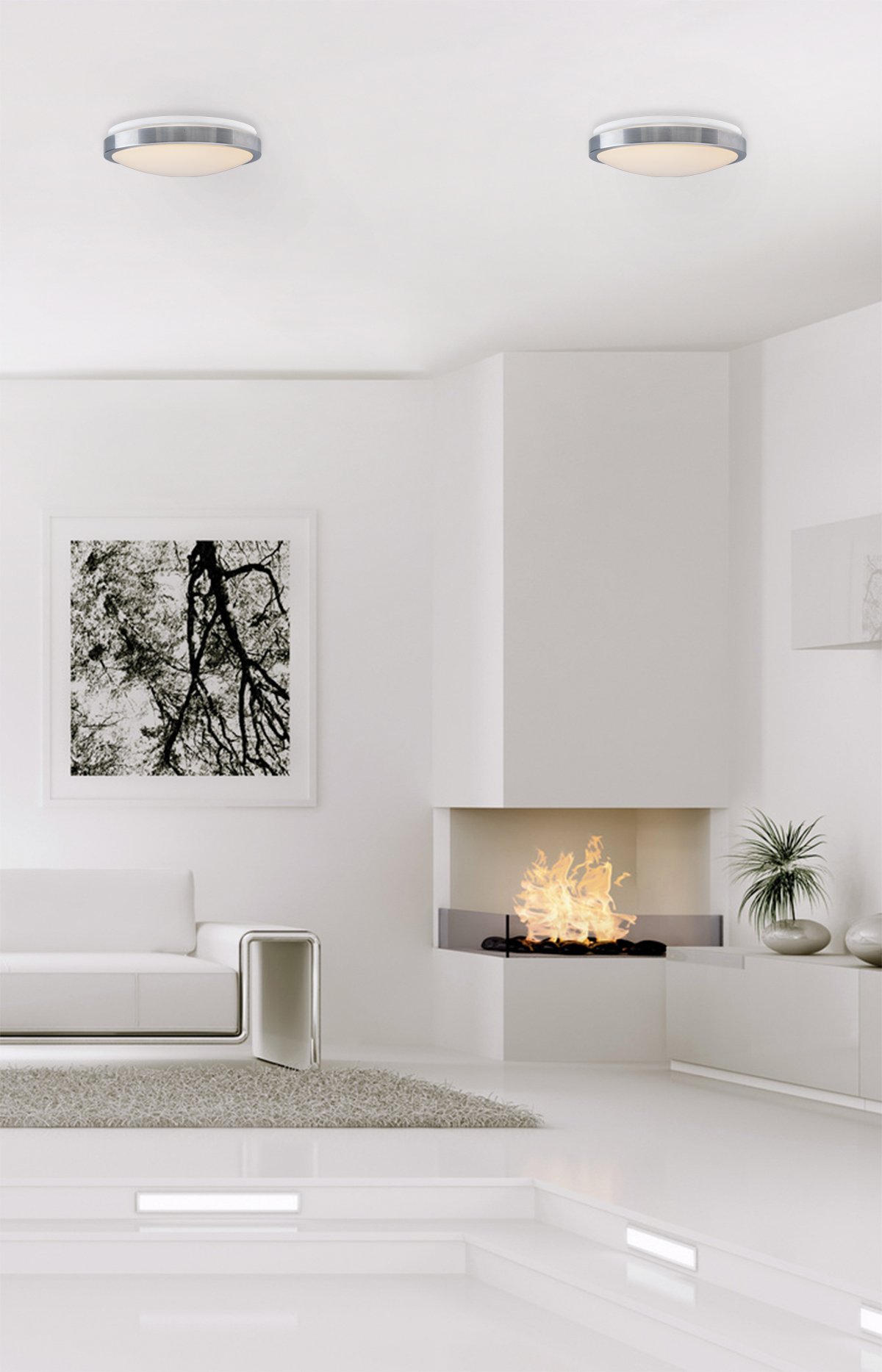 Ein modernes, weißes Zimmer mit Kamin, Sofa und zwei Deckenleuchten. Ein Bild hängt an der Wand.