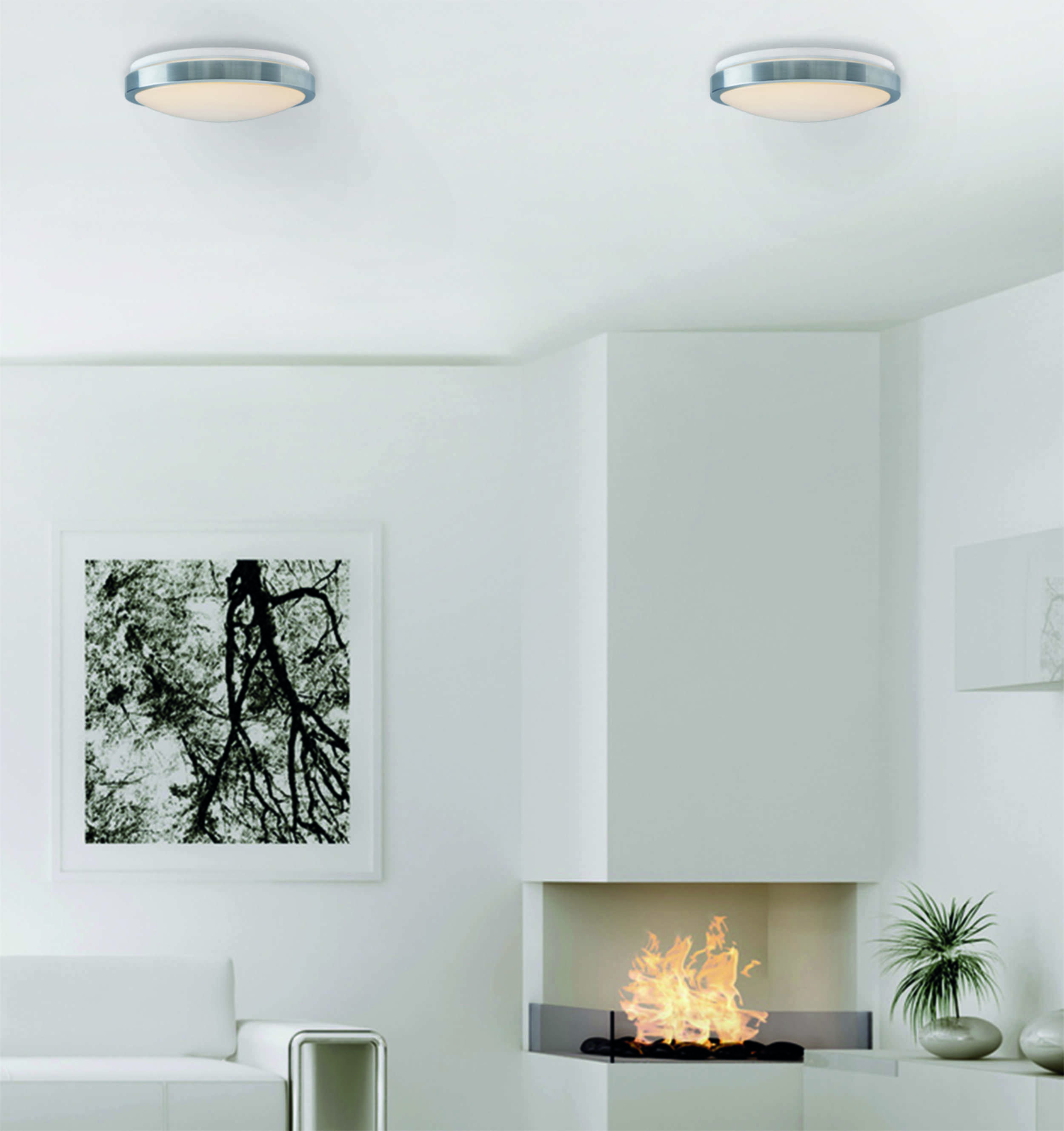 Ein modernes, weißes Zimmer mit Kamin, Sofa und zwei Deckenleuchten. Ein Bild hängt an der Wand.