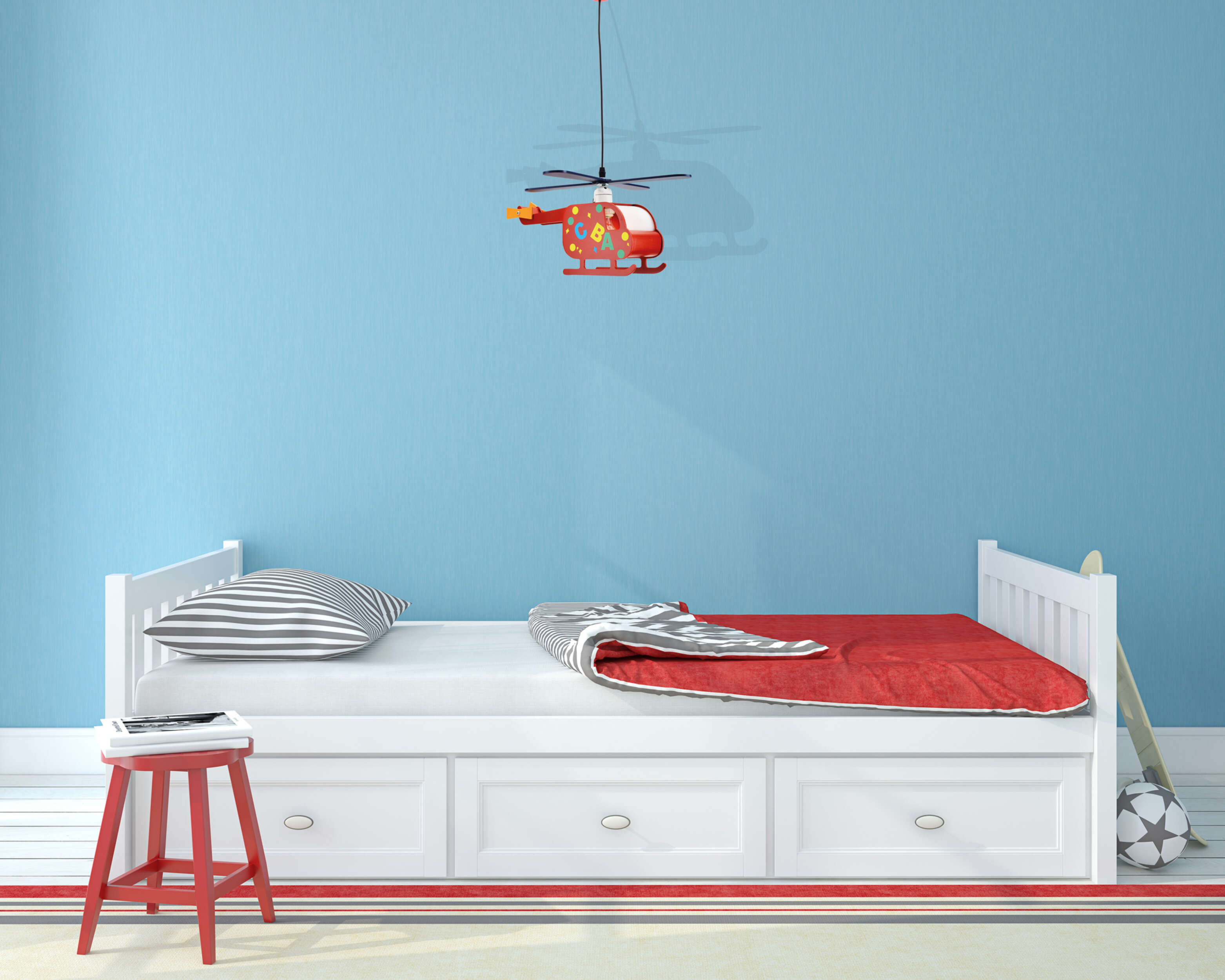 Ein Kinderzimmer mit weißem Bett, rotem Hocker und einem hängenden Hubschrauberspielzeug.