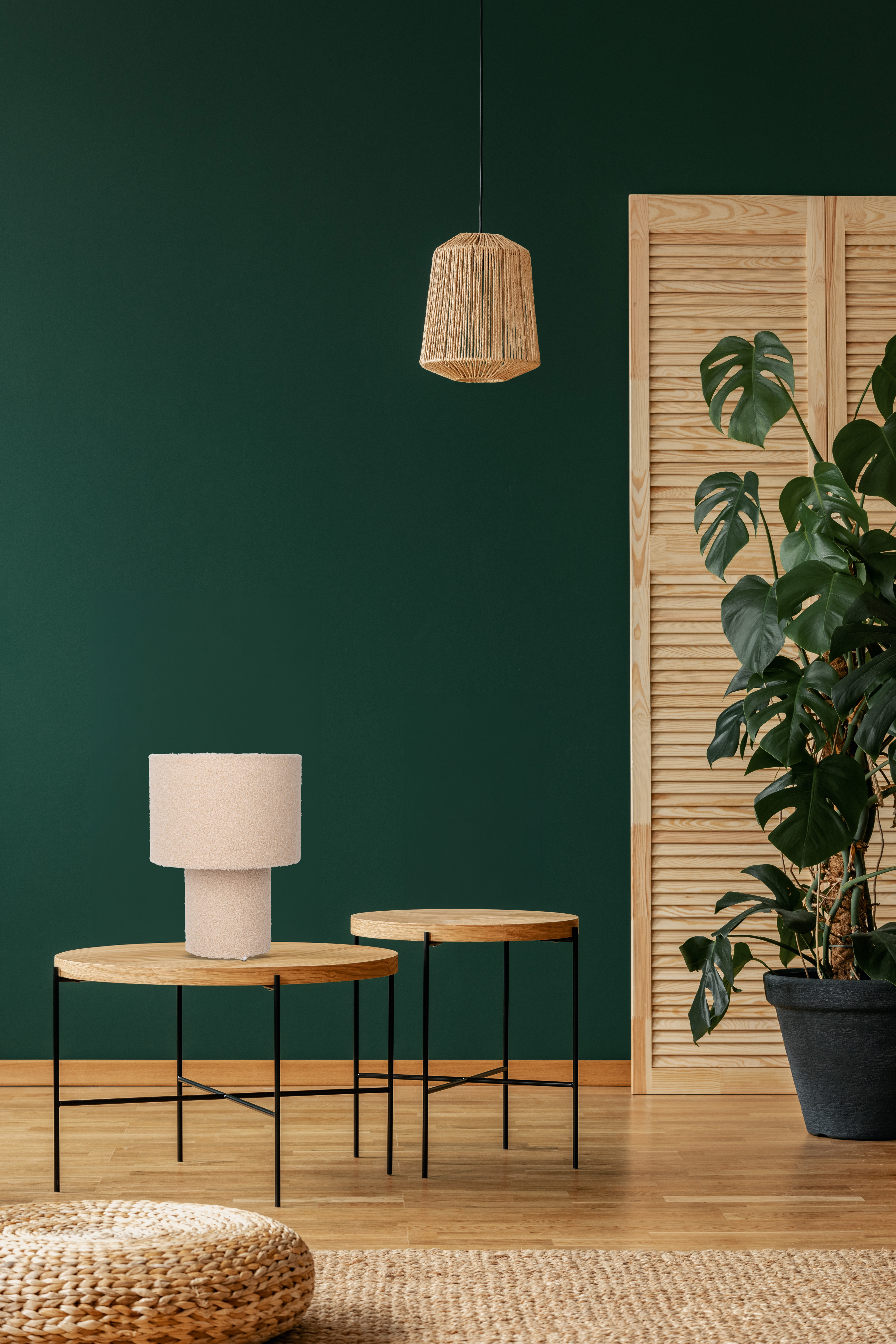Ein Raum mit grüner Wand. Zwei Holztische mit Lampe und Pflanze im Hintergrund.