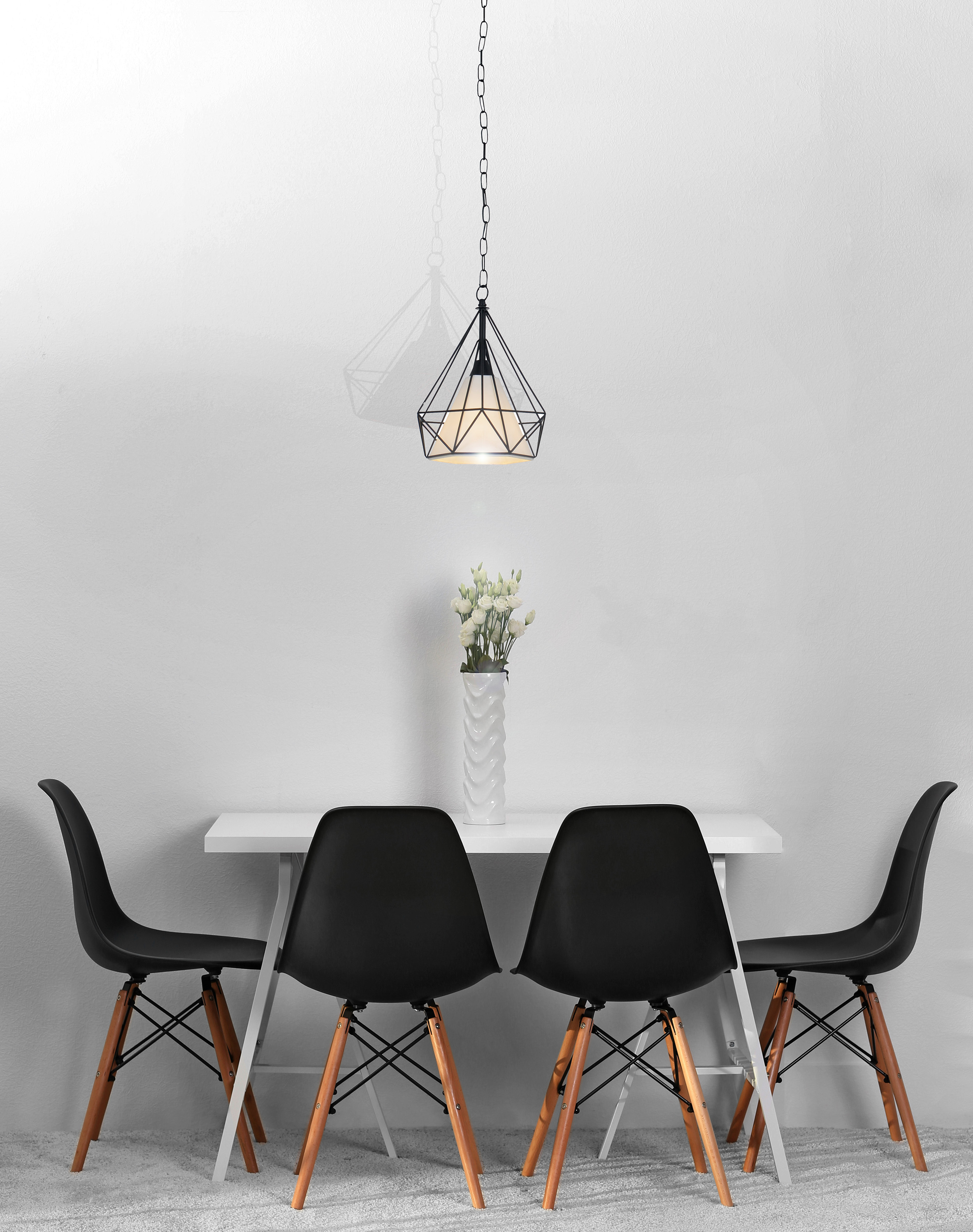 Esszimmer mit schwarzen Stühlen, weißem Tisch und schwarzer geometrischer Pendelleuchte. Weiße Wände.
