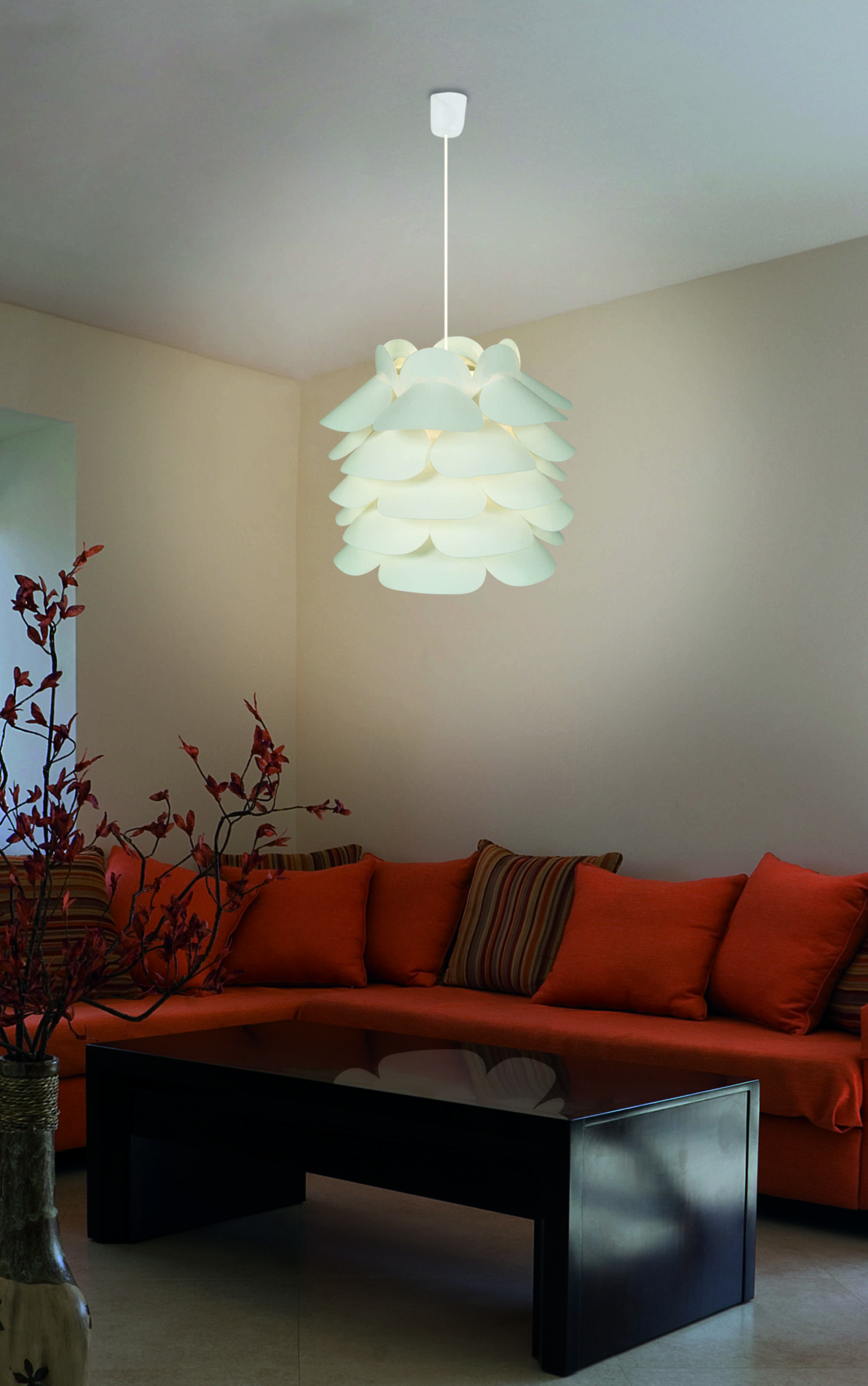Eine weiße Hängeleuchte über einem orangenen Sofa in einem Wohnzimmer.
