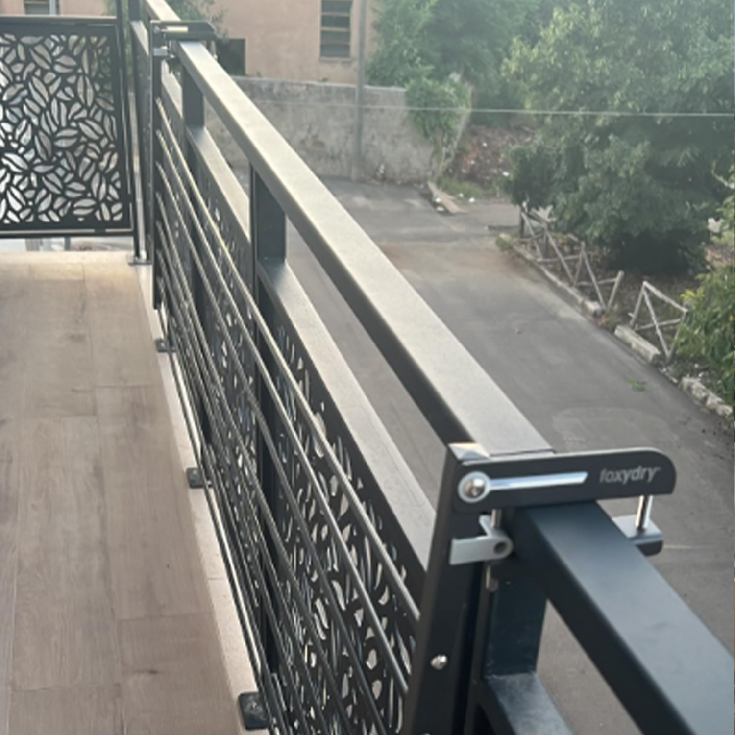 Ein schwarzes Metallgeländer auf dem Balkon mit Blick auf eine Straße und umliegende Gebäude.