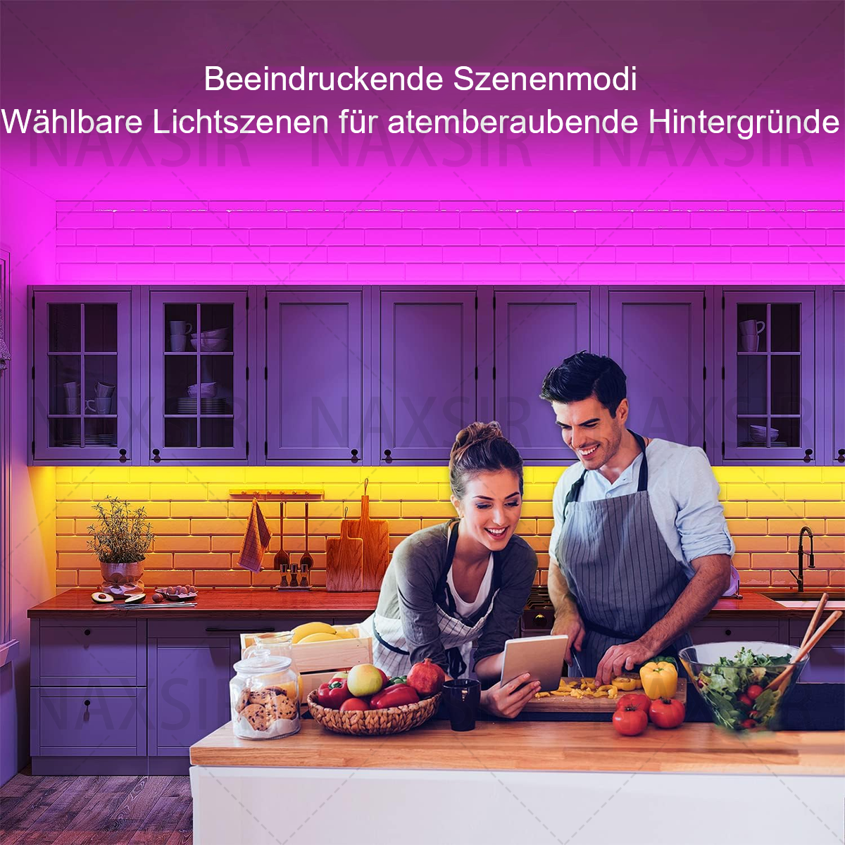 Paar in der Küche. Sie schauen auf ein Tablet. Die Küche hat Schränke und ist mit farbigen Lichtern beleuchtet.