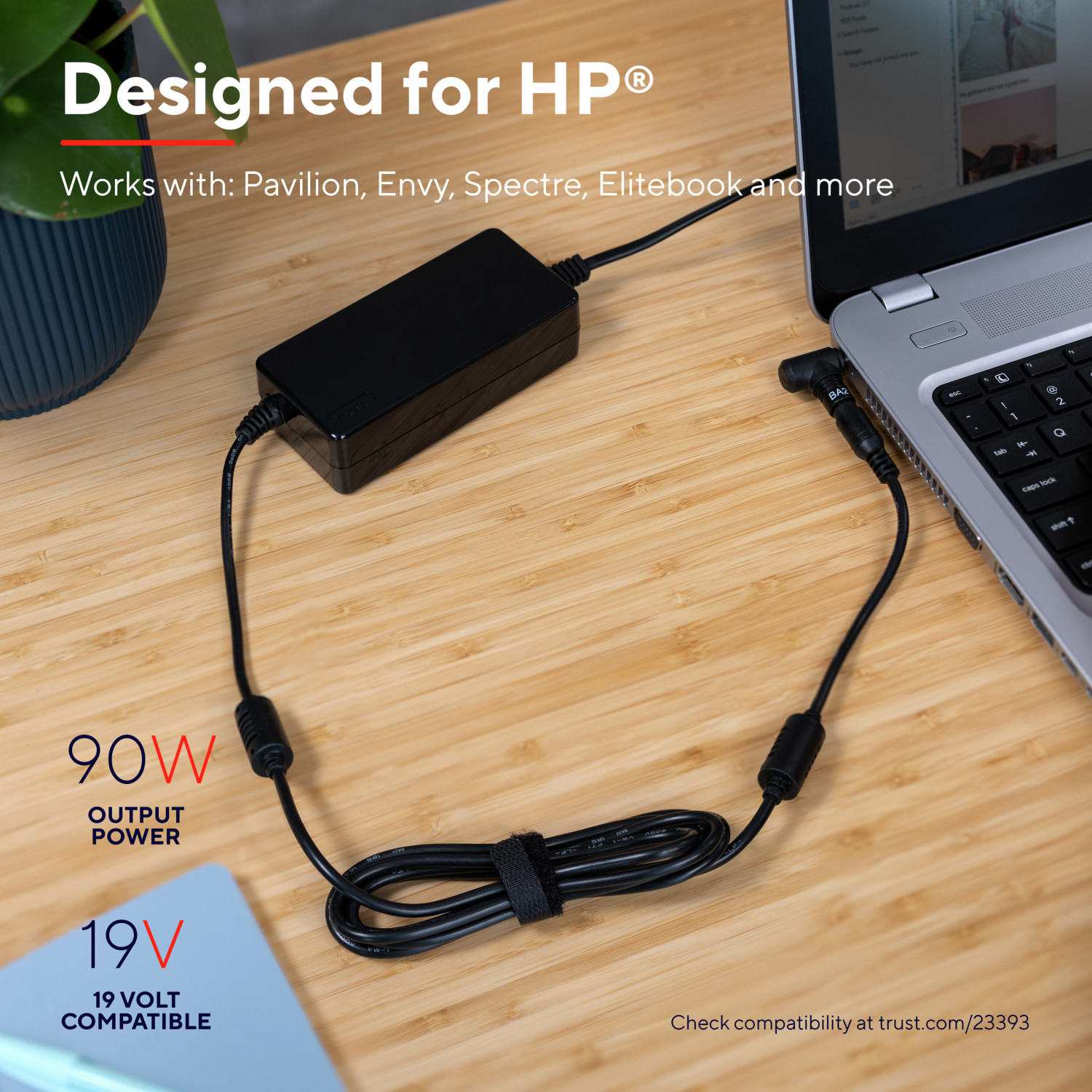Cargador de portátil con adaptador y cable negros. El portátil está abierto, sobre madera.