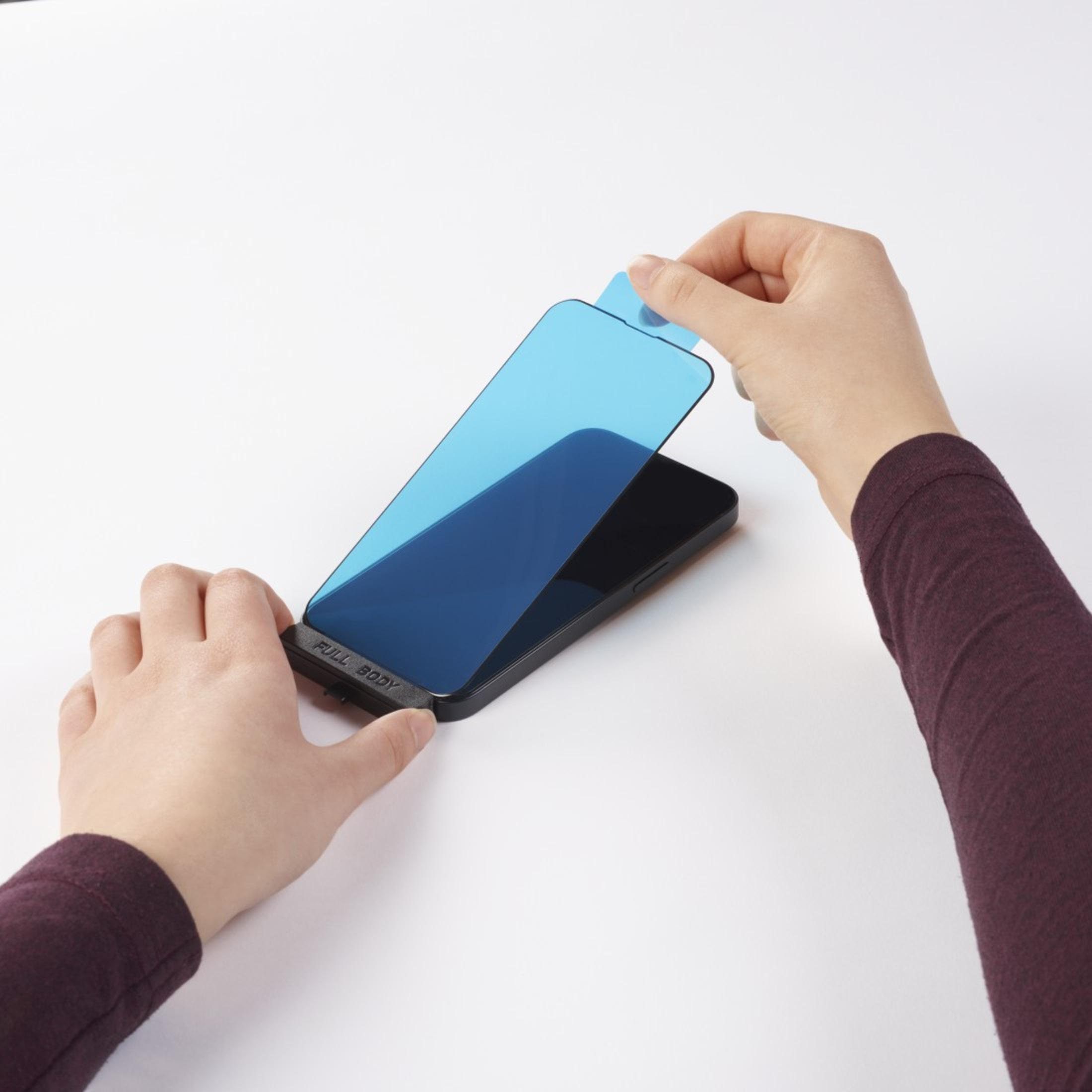 Osoba nakłada niebieski ochraniacz ekranu na czarny telefon.