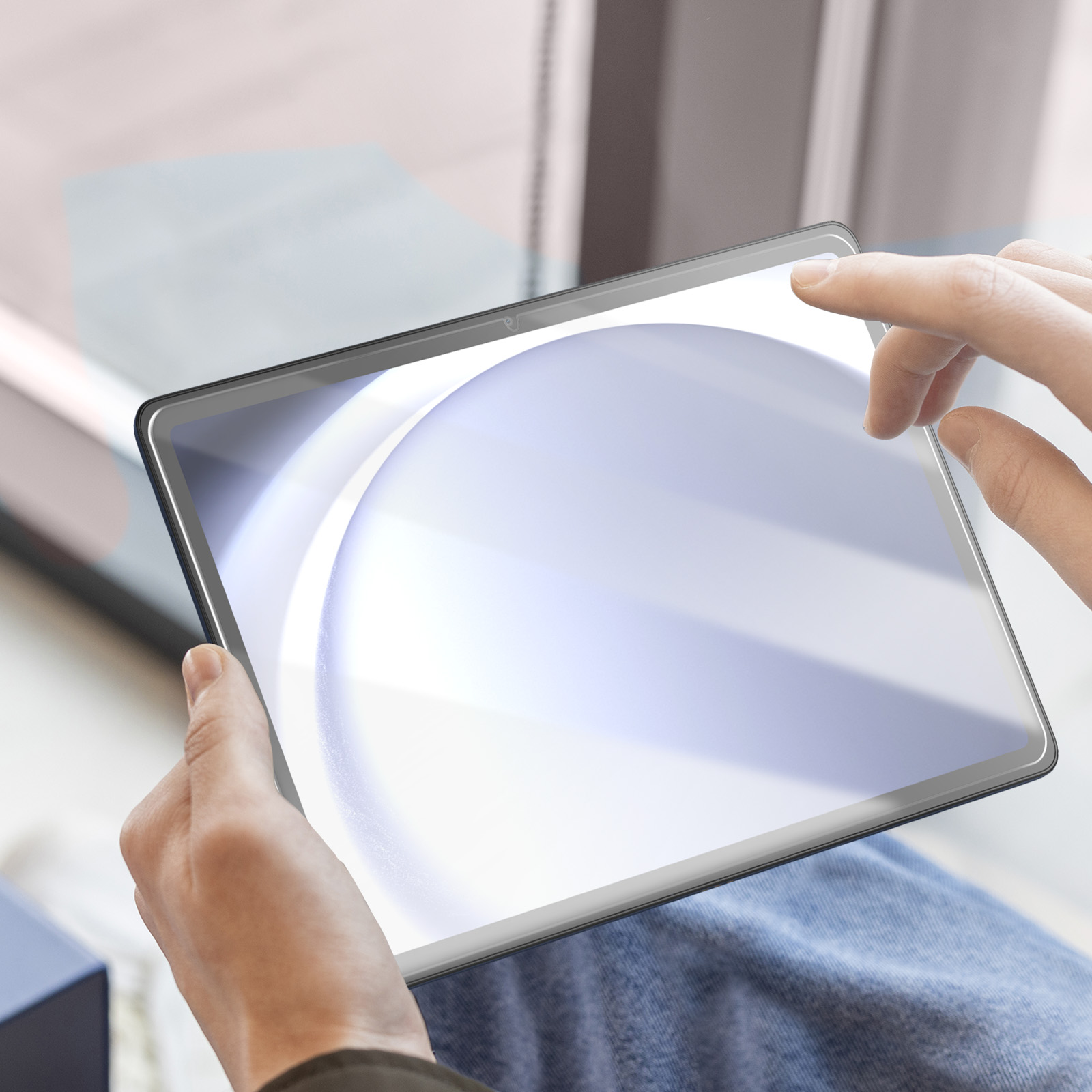 Mani che tengono un tablet con protezione schermo e sfondo sfocato.