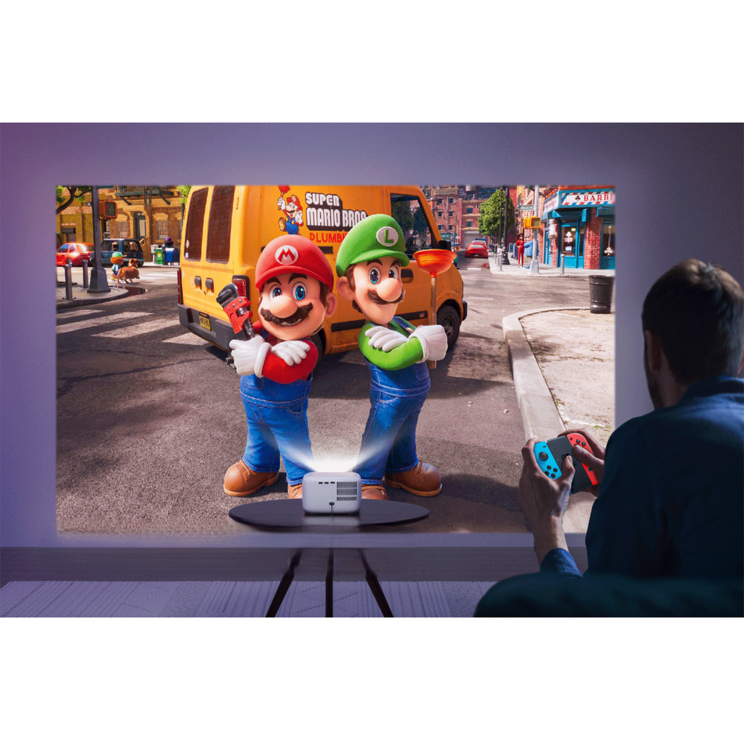 Un uomo gioca su un grande schermo. Mario e Luigi sono sullo schermo.