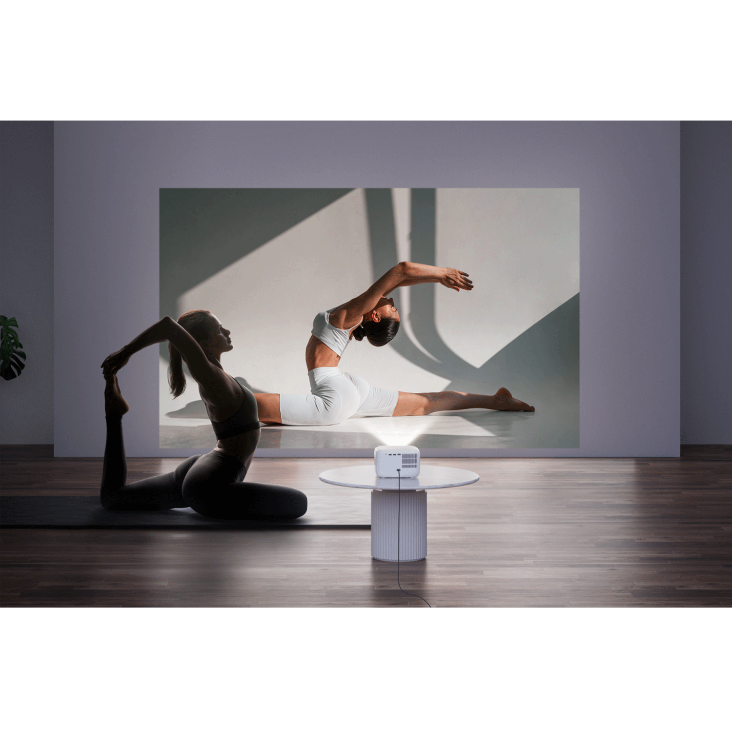 Un proiettore su un tavolo mostra immagini di pose yoga su un muro. Una donna fa yoga davanti alla proiezione.