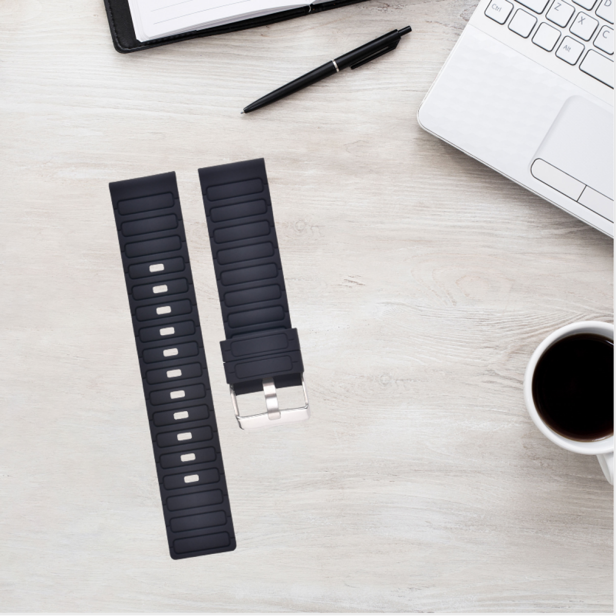 Zwei schwarze Uhrenarmbänder auf einer Holzoberfläche. Ein schwarzer Stift, Notizbuch und Laptop sind sichtbar.