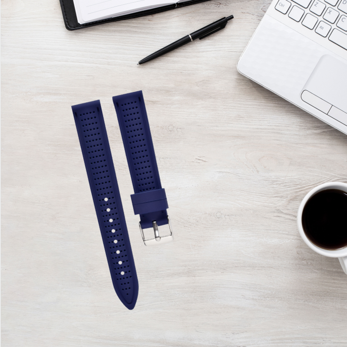 Cinturini per orologi su una superficie in legno, con un laptop, una penna e una tazza di caffè nelle vicinanze.